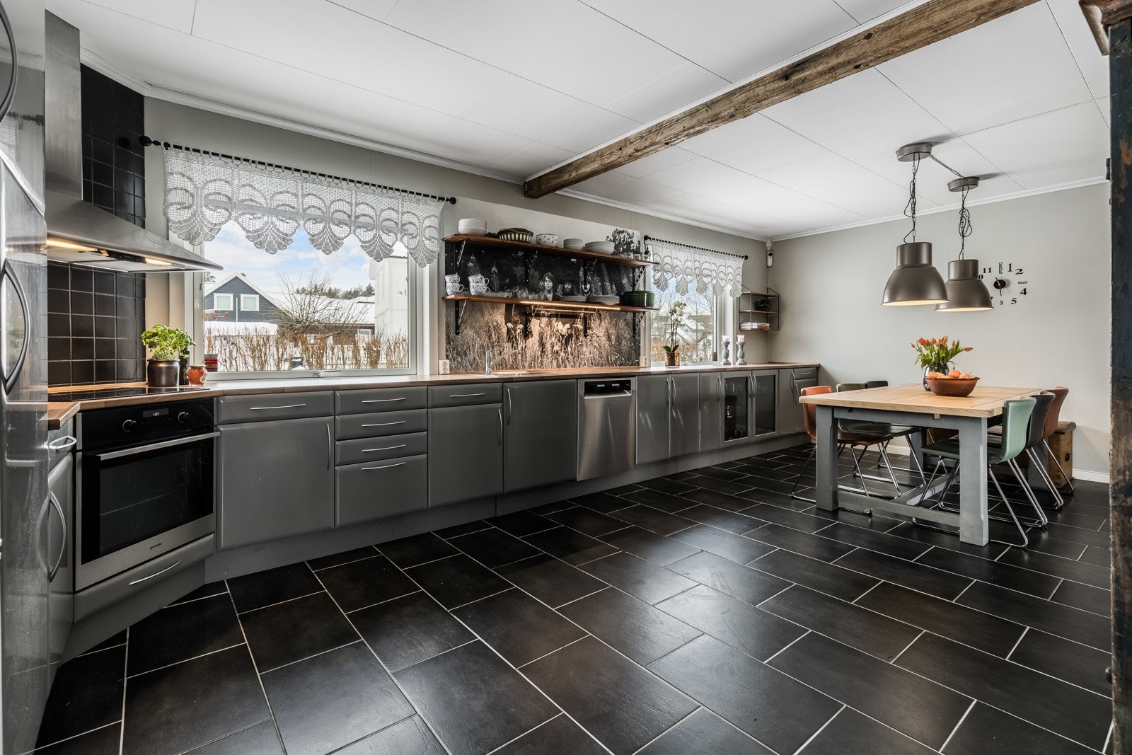 Pent kjøkken med glatte, sølvgrå fronter og laminert benkeplater. Galleribilde