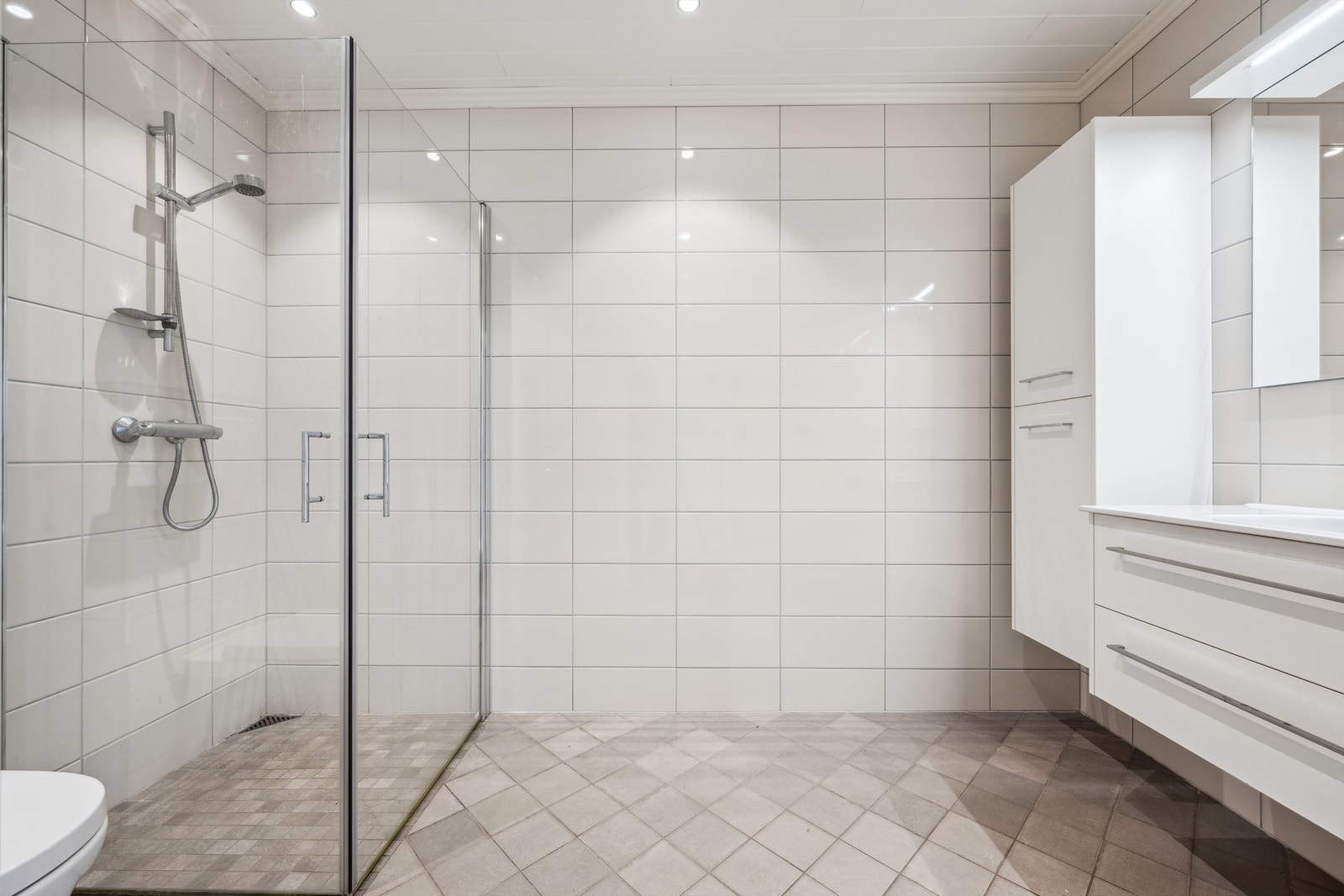 Bad har flislagte vegger og gulv, og malte himlingsflater med downlights Galleribilde