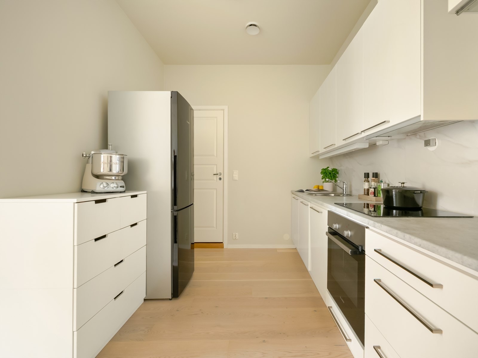 Innredningen har hvite, glatte folierte fronter som gir et tidløst preg. Benkeplaten er i laminat og har nedfelt kum i rustfritt stål. Galleribilde