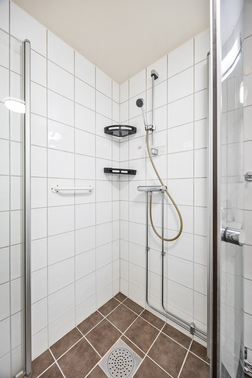 Badet er utstyrt med dusjhjørne med innfellbare glassvegger og servantinnredning med skuffer og overskap Galleribilde