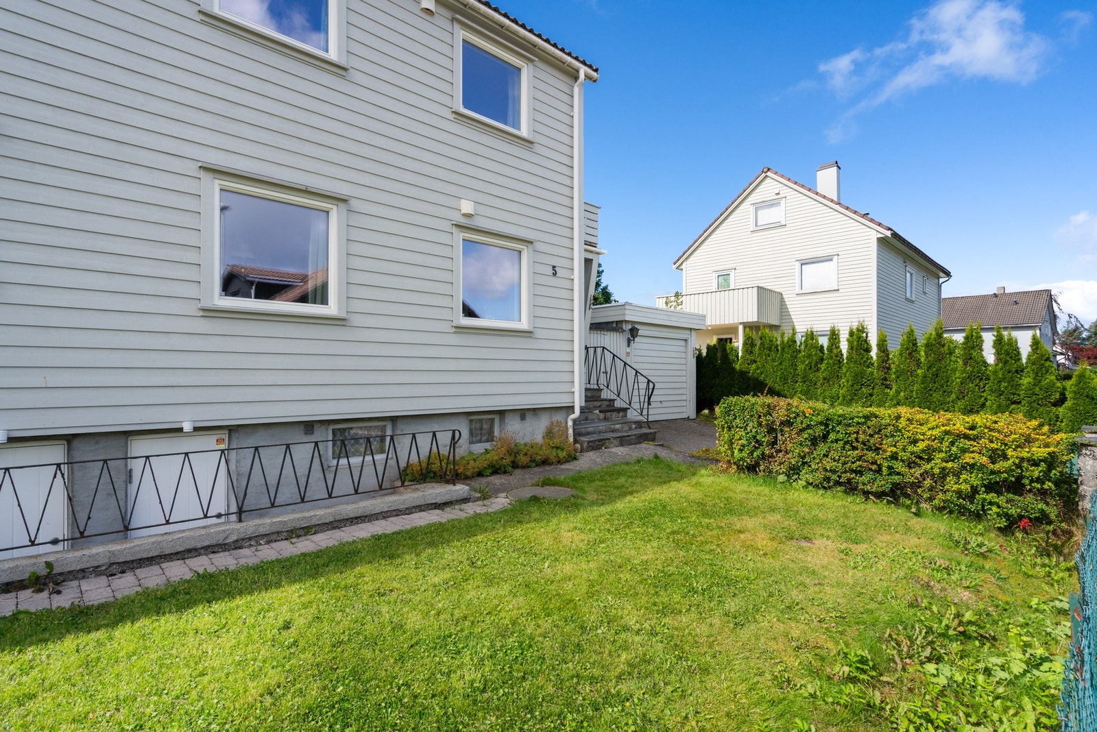 Liten hageflekk på fremsiden av boligen med egen inngang til kjeller for enkel adkomst. Galleribilde
