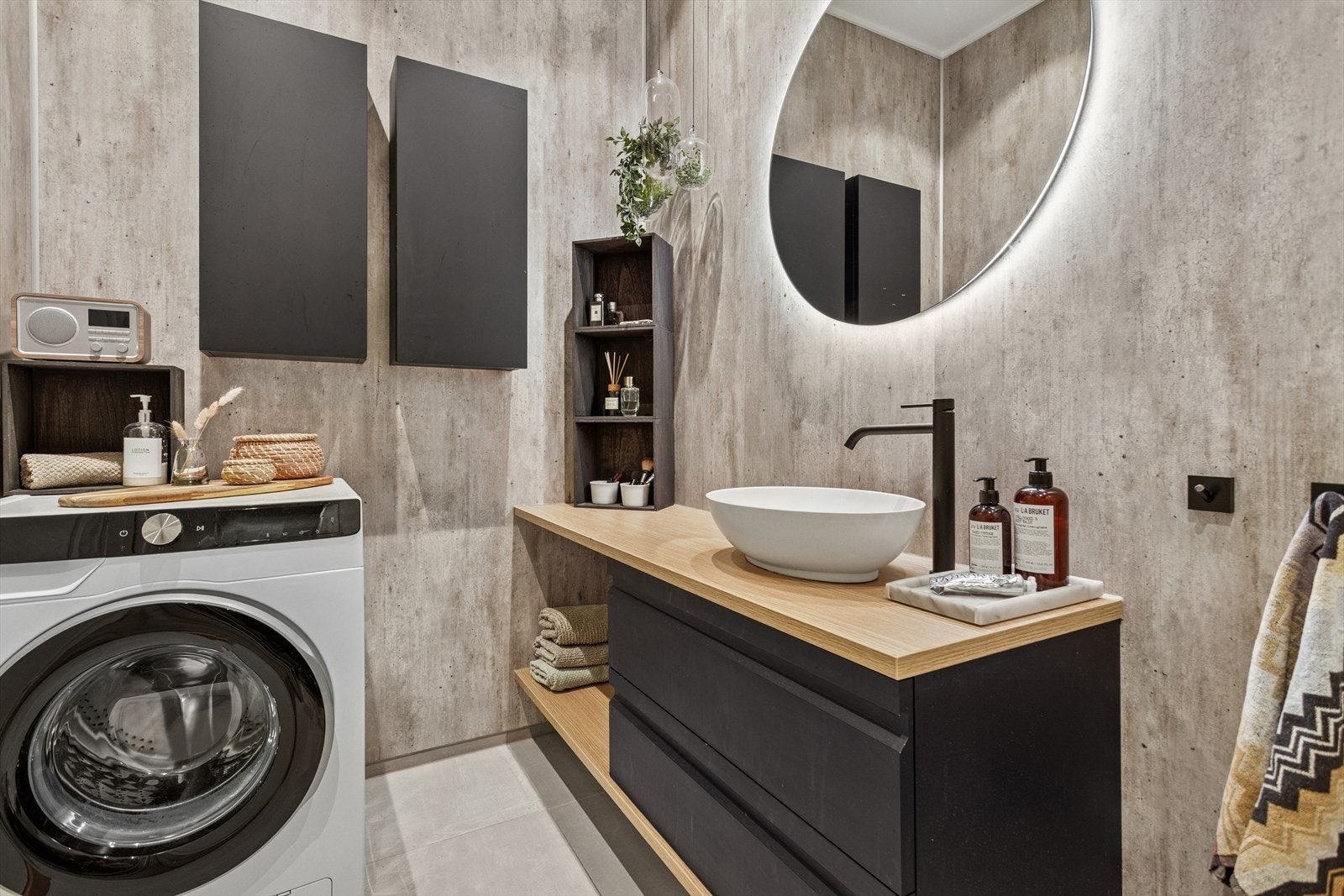 Baderommet er innredet med servant i stilren baderomsinnredning, vegghengt toalett, dusjhjørne med glassvegger samt opplegg for vaskemaskin Galleribilde