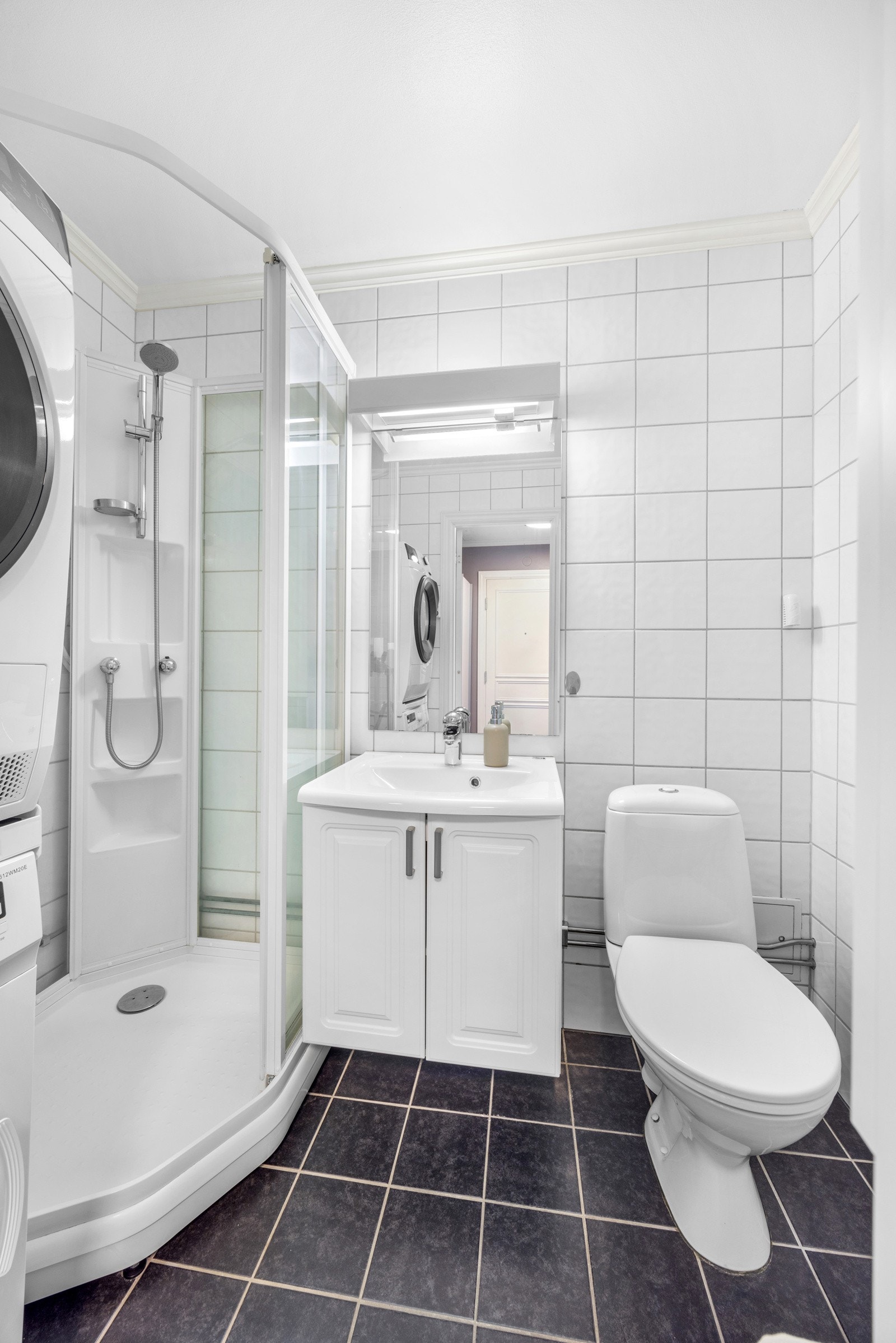 Badet er innredet med toalett, dusjkabinett, servant med underskap og opplegg til vaskemaskin. Galleribilde