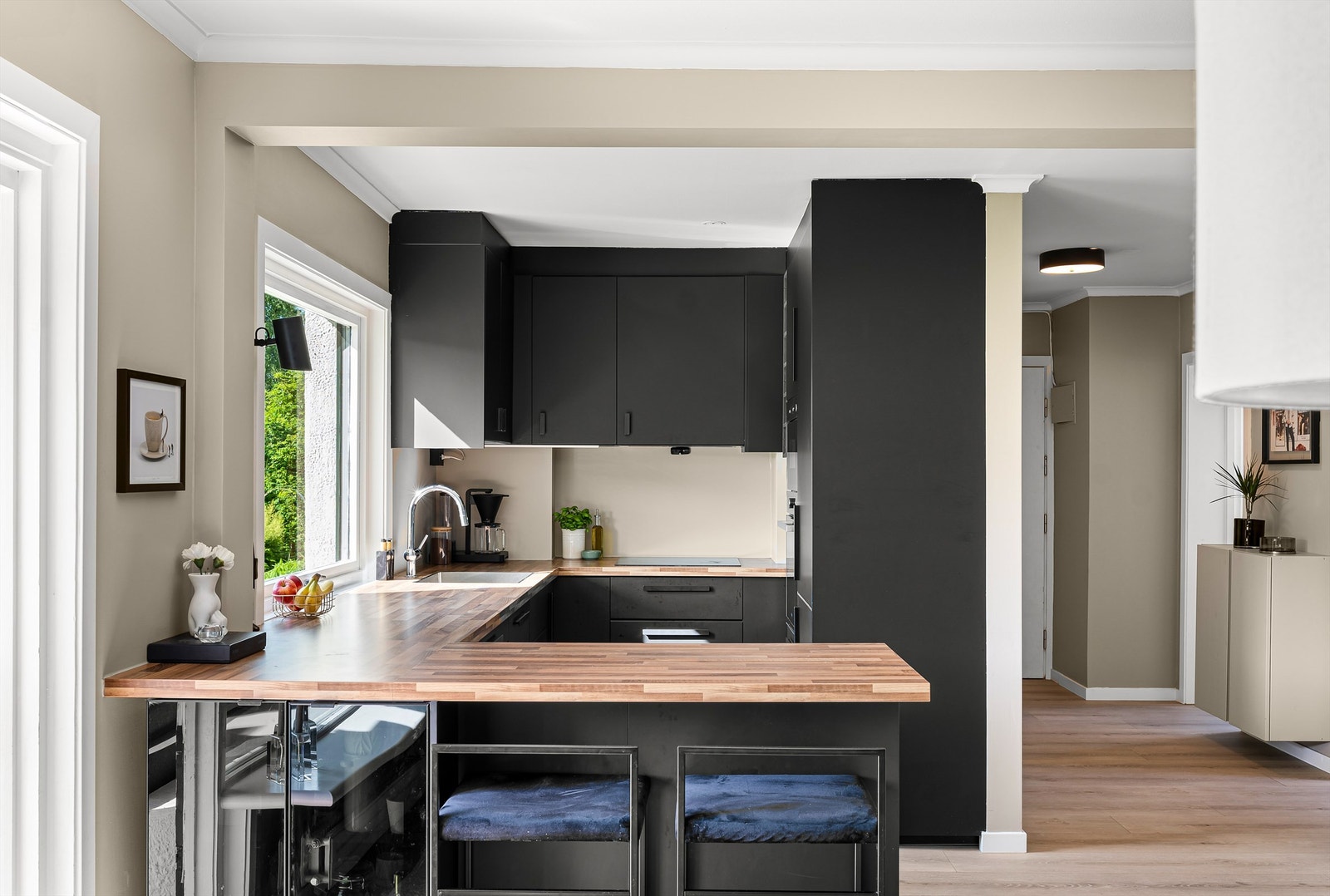 Kjøkkenet ble pusset opp i 2018, og har en stilren innredning med mørke, glatte fronter og laminat benkeplate med planlimt oppvaskkum i rustfritt stål. Det er belysning under overskap og ventilator med avtrekk til ventilasjonskanal. Galleribilde