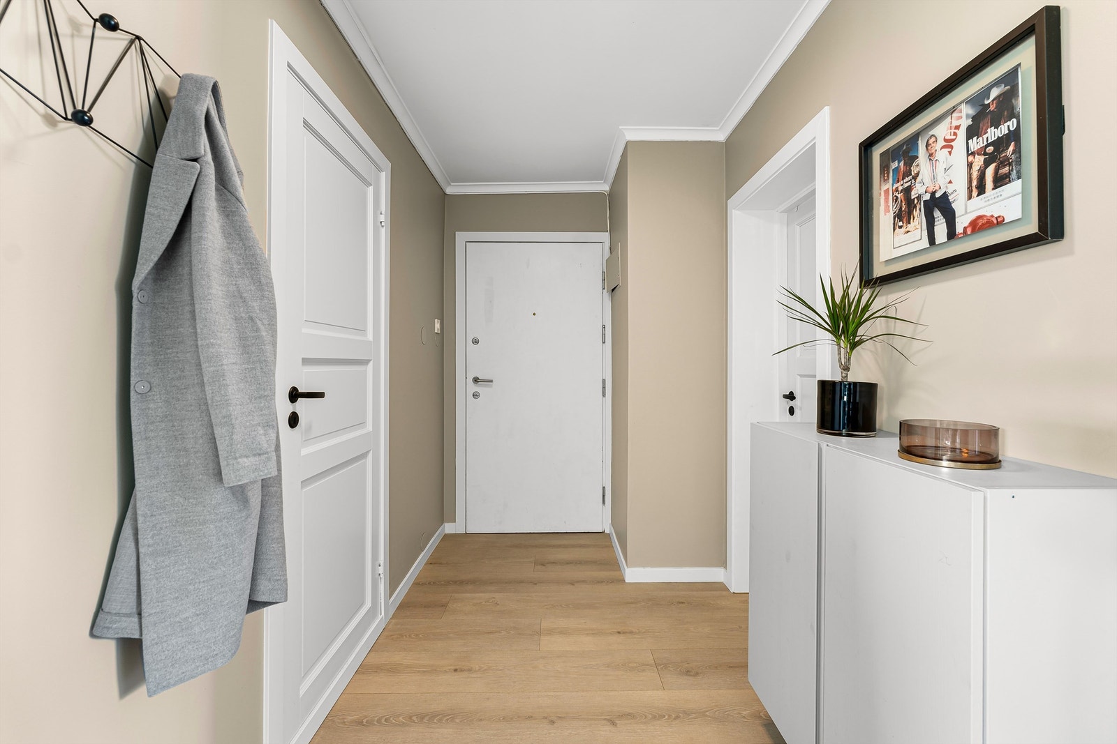 Lys og innbydende entré med god plass til oppbevaring av yttertøy og sko, med praktisk planløsning som gir tilgang til leilighetens øvrige rom. Galleribilde