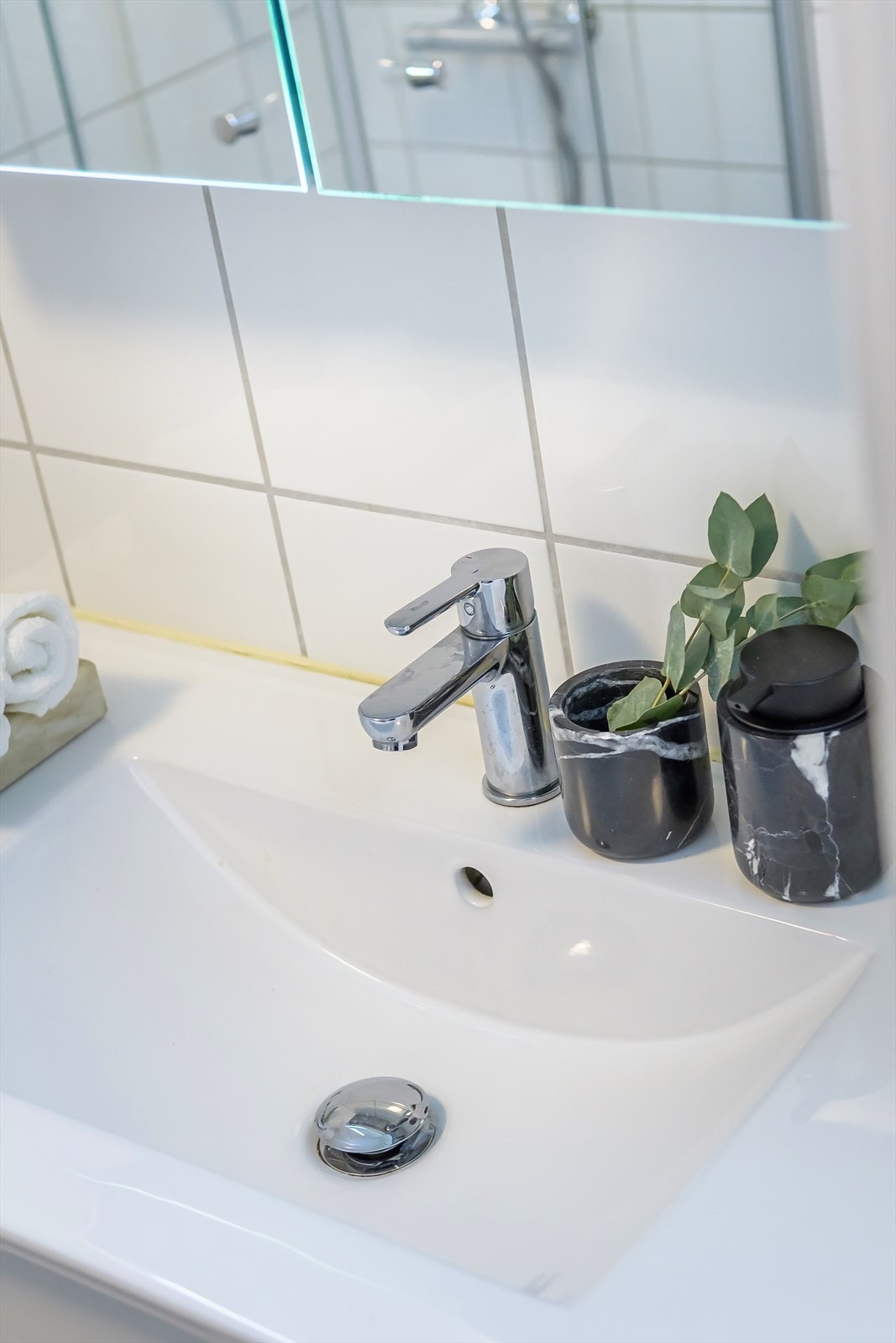 Badet er innredet med klosett, servant med innredning, speilskap med lys, og dusjhjørne med svingbare glassdører. Galleribilde