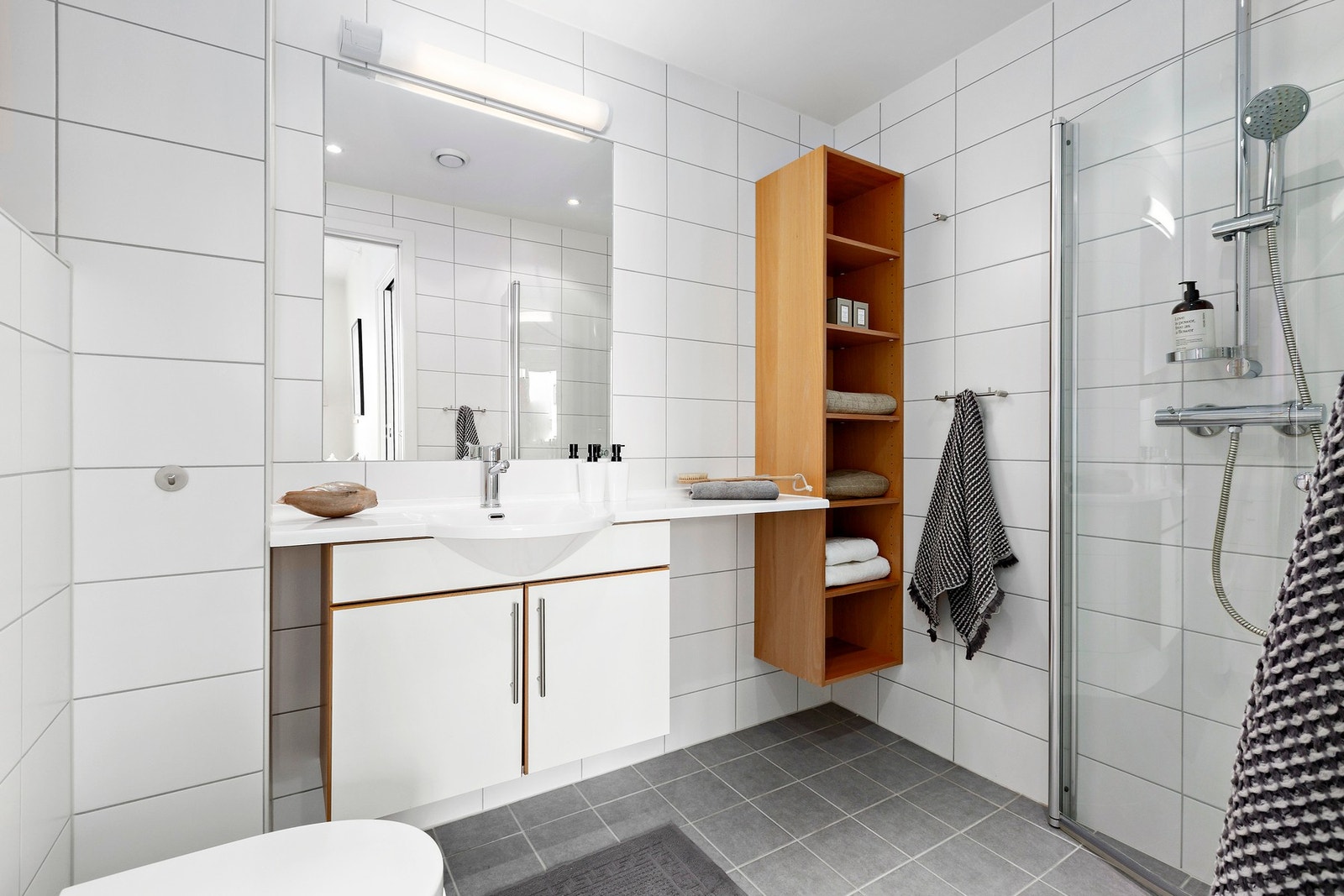 Bad en suite har dusjhjørne med innfellbare dusjdører, vegghengt toalett og romslig baderomsinnredning med speil og belysning. Galleribilde