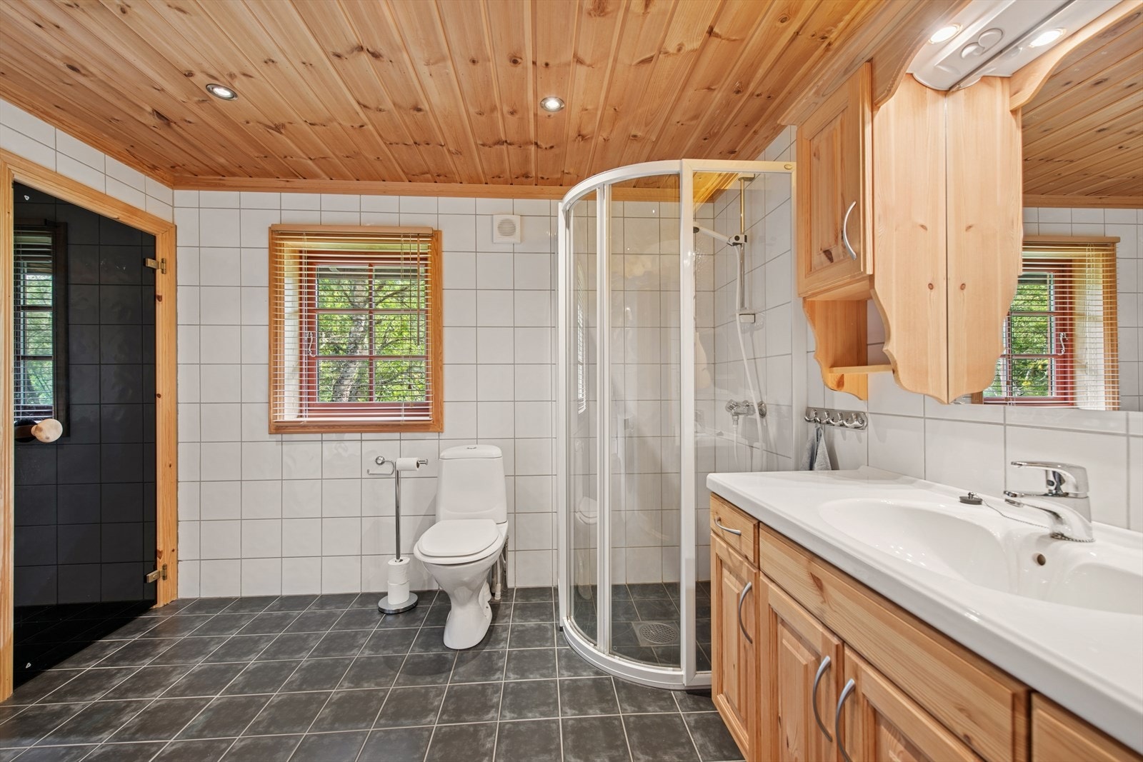 Badet fremstår som funksjonelt og velholdt, med fliser på både gulv og vegger, panel i taket og behagelig gulvvarme. Galleribilde