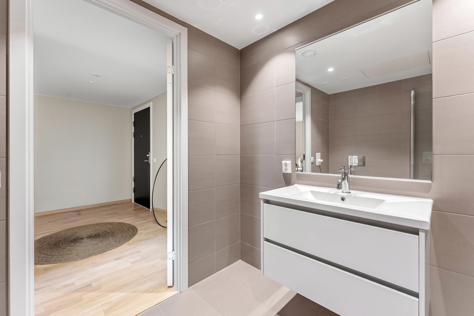 Badet er utstyrt med dusjnisje med glassdører, vegghengt toalett og servant med innredning. Galleribilde