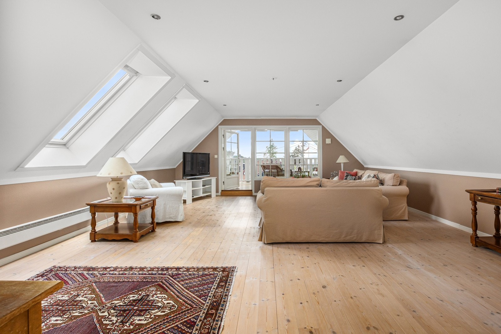 Loftstuen er lys og trivelig med store vindusflater mot terrassen og dagslys fra to takvinduer. Galleribilde
