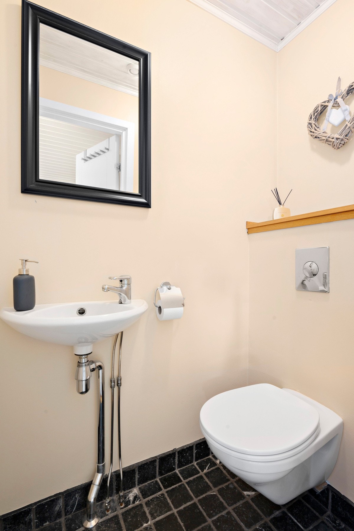 Praktisk wc-rom i entré innredet med vegghengt toalett og servant Galleribilde