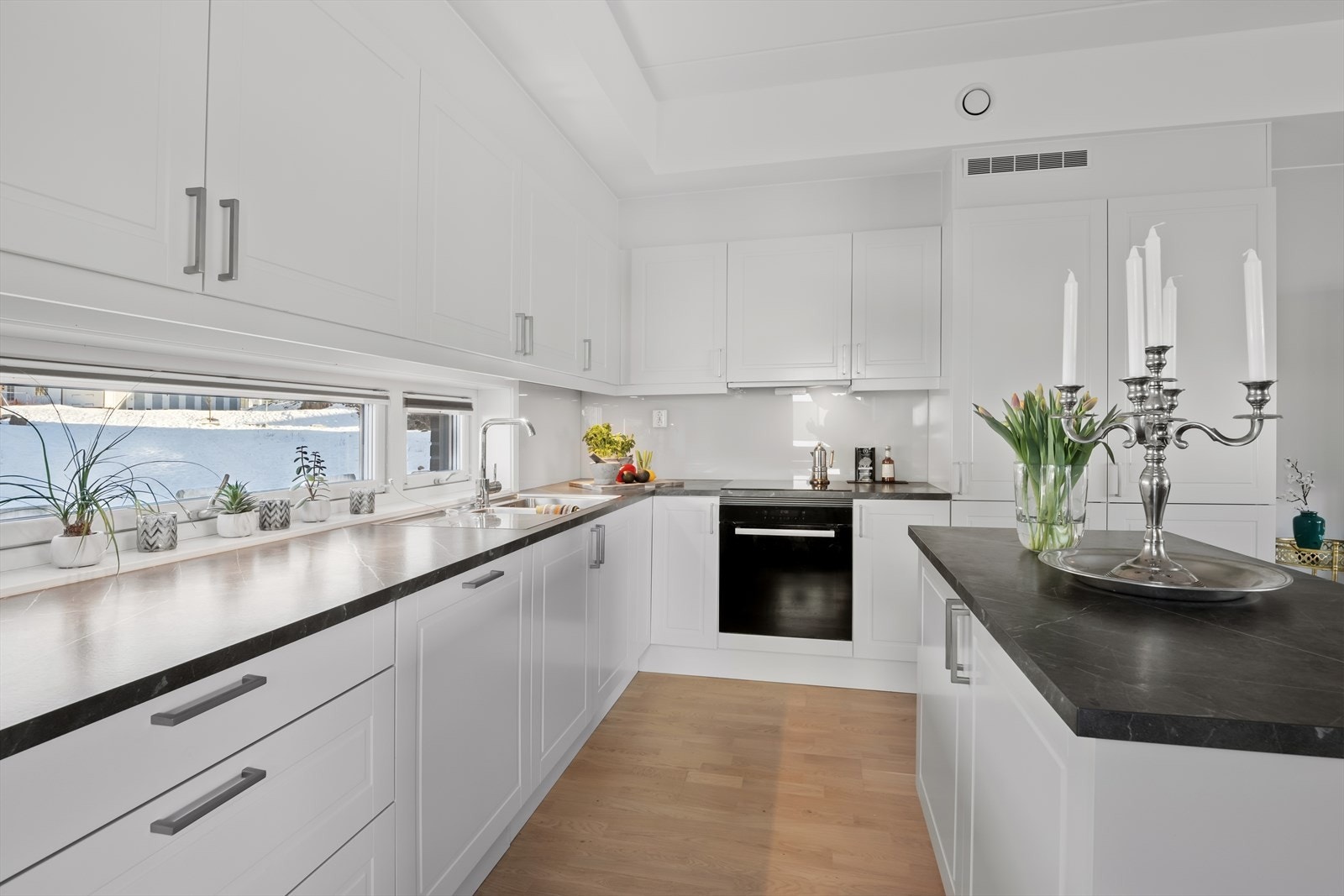 Videre byr kjøkkenet på detaljer som belysning under overskap, stor kjøkkenvask, montert glassplate på vegg mellom benkeplate og overskap og vindu mellom benkeplate og overskap som sikrer godt med dagslys. Galleribilde