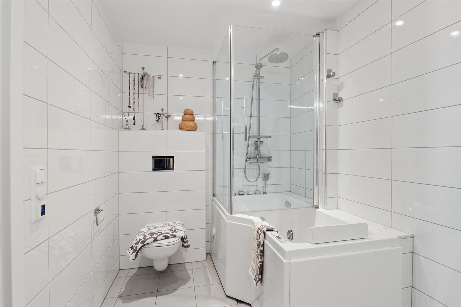 Badet er innredet med en praktisk og stilfull innredning med skuffeseksjon og heldekkende servant, belyst speilskap for oppbevaring og vegghengt toalett. Galleribilde