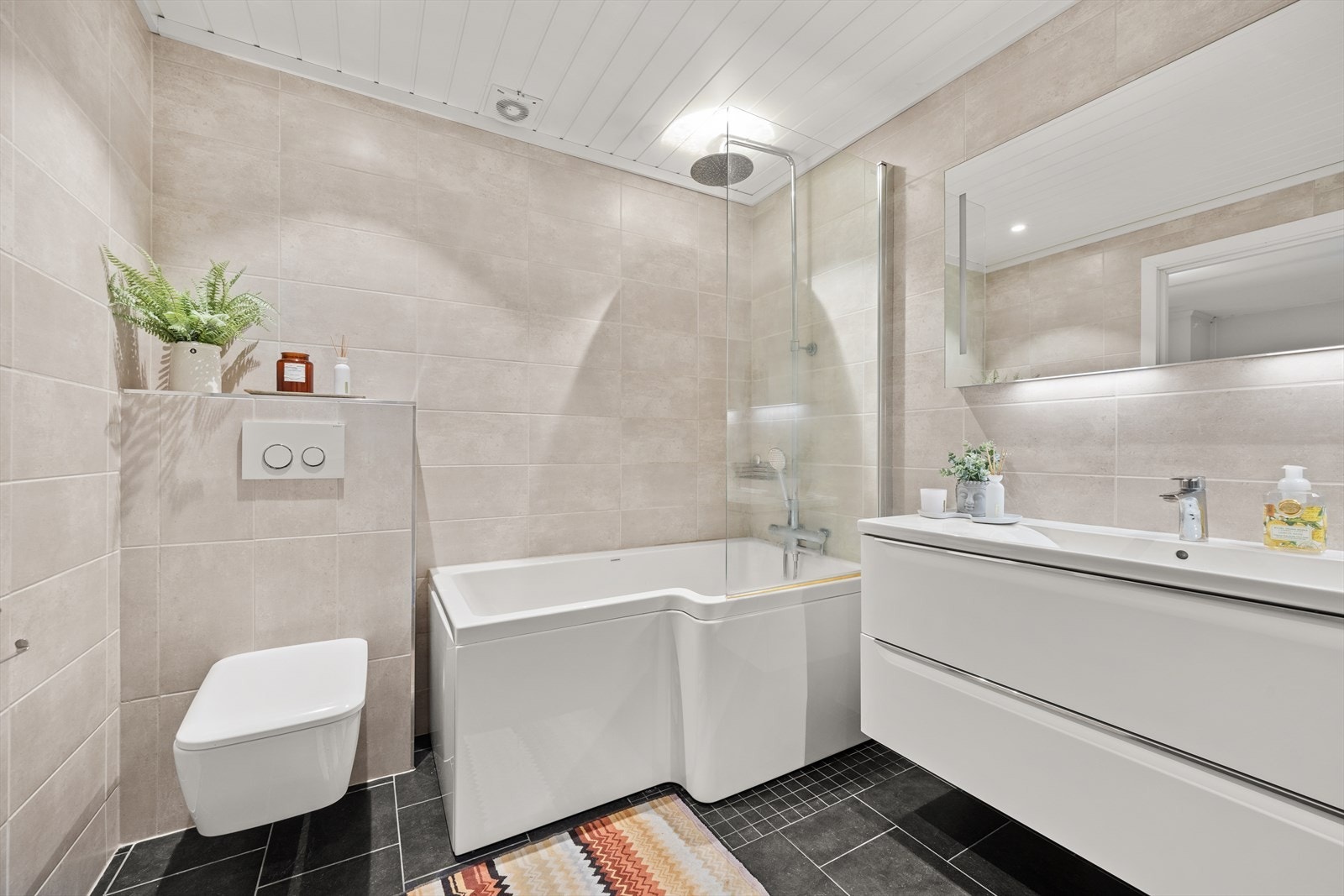 Badet er utstyrt med heldekkende servant med underskap, veggskap, badekar med regndusj, toalett samt opplegg for vaskemaskin og tørketrommel Galleribilde