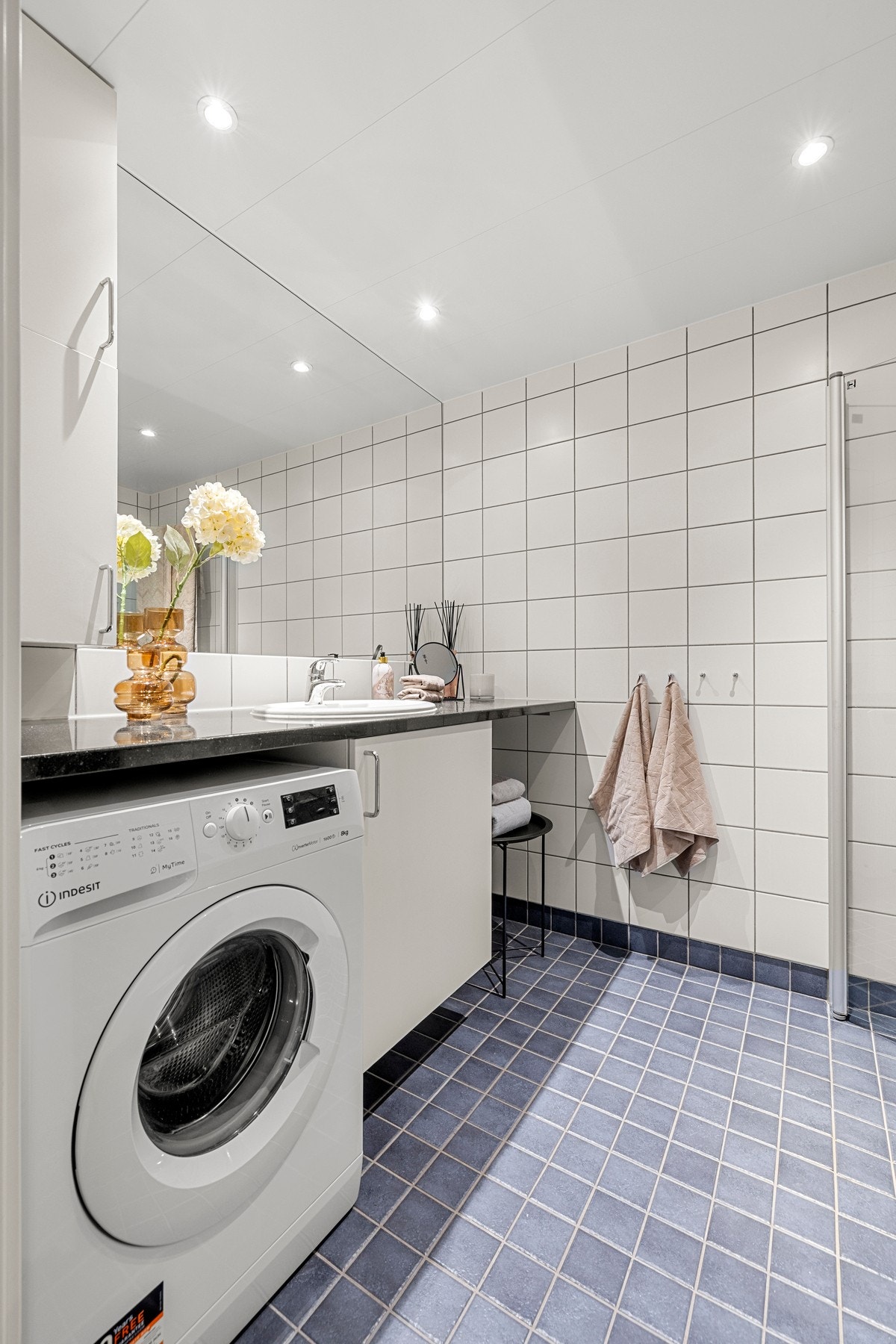 Badet er fra byggeår, og har et tidløst uttrykk med grå gulvfliser og hvite veggfliser. Det er varmekabler i gulvet, og downlights i himling. Galleribilde