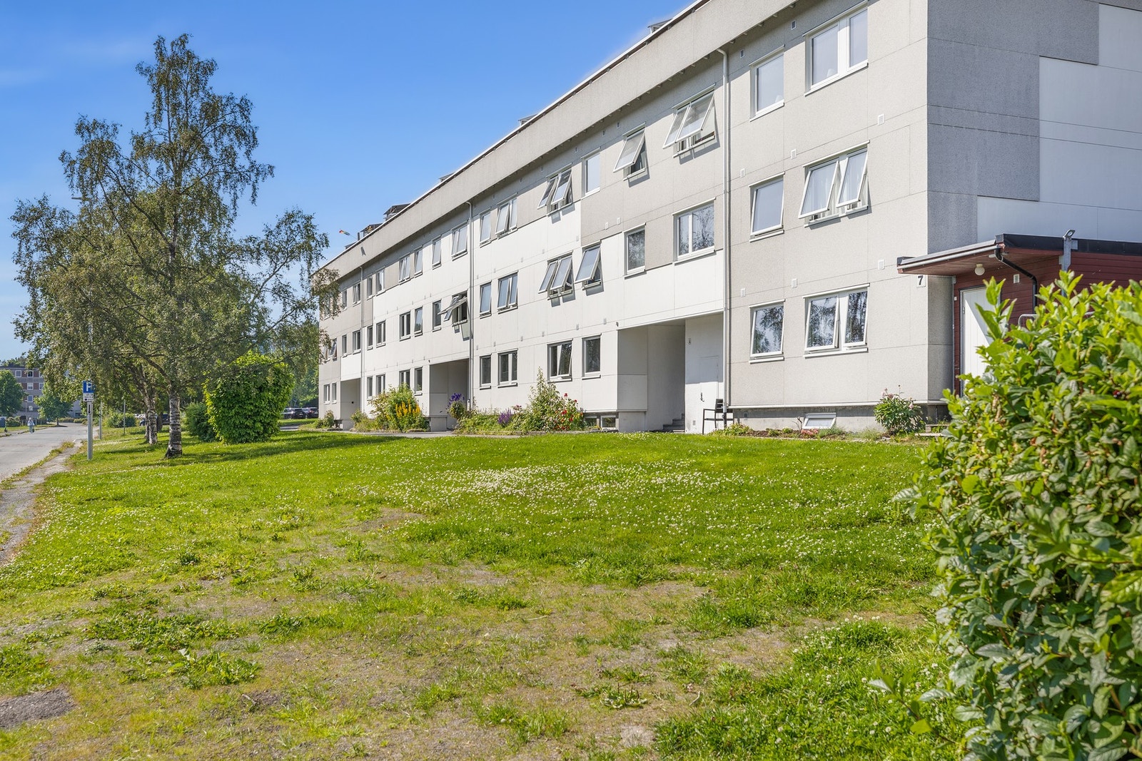 Fasade og uteområde. Borettslaget har store grøntareal med flere sitteplasser. Galleribilde