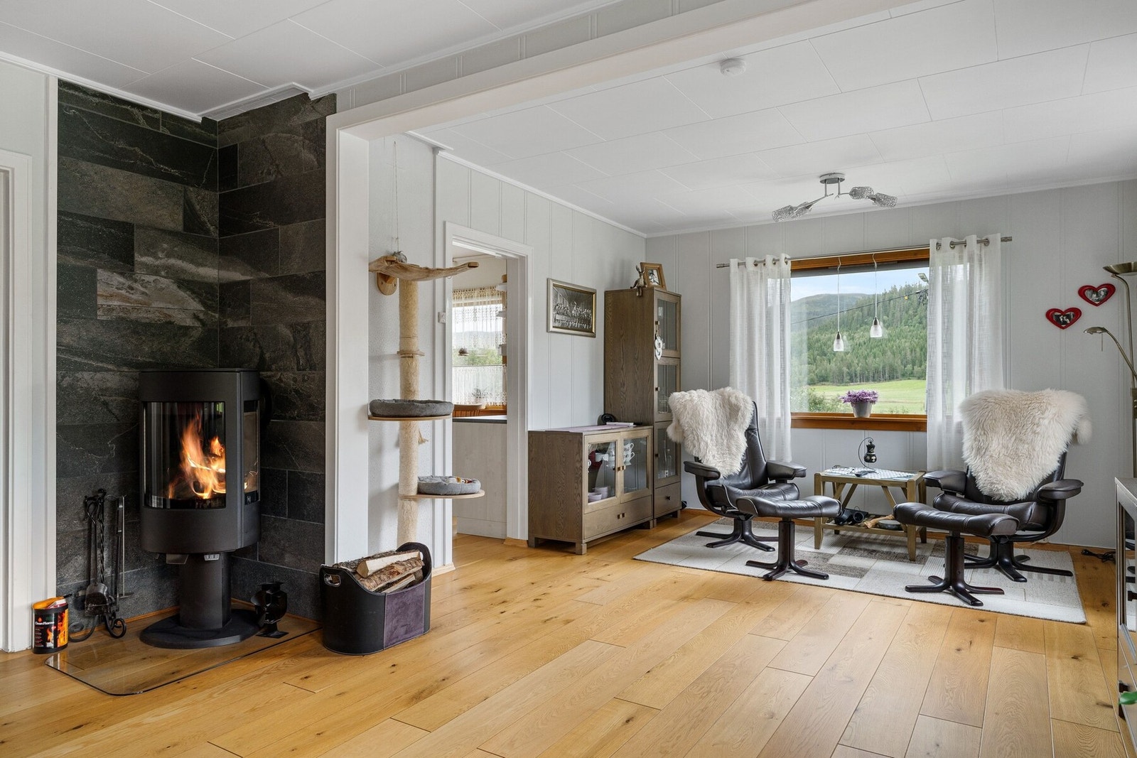 Her er det en vedovn fra 2020, med flislagt bakvegg som gir det lyse rommet en fin kontrast. Galleribilde