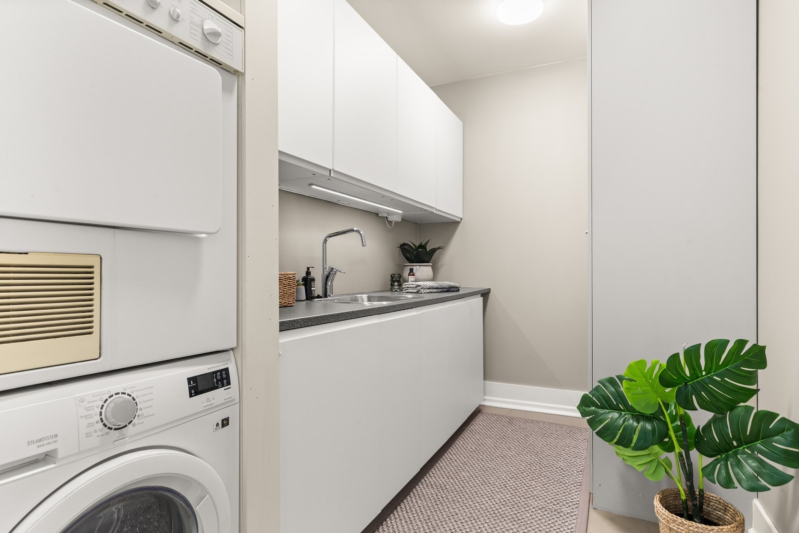 Vaskerommet er praktisk til klesvasken og bidrar til at man slipper å ha klærne hengende rundt til sjenanse i de øvrige rommene . Opplegg for vaskemaskin og tørketrommel og rikelig med oppbevaring. Gulvvarme. Galleribilde