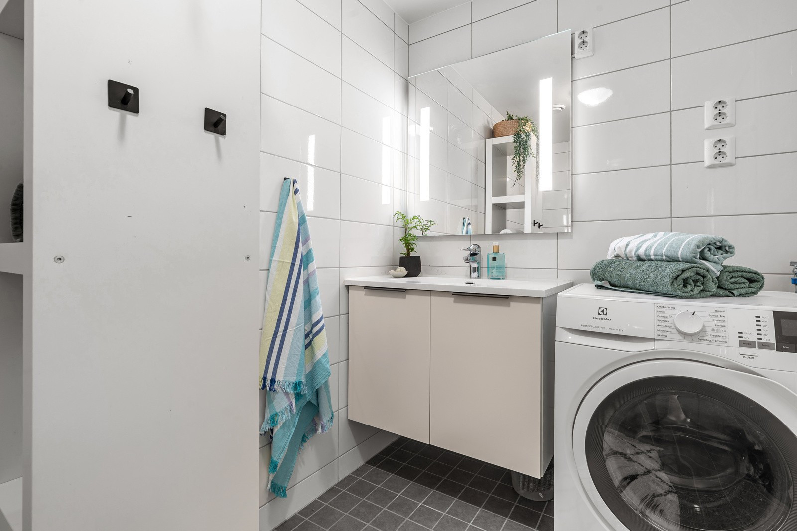 Badet har lys baderomsinnredning med heldekkende servant, speil og belysning.