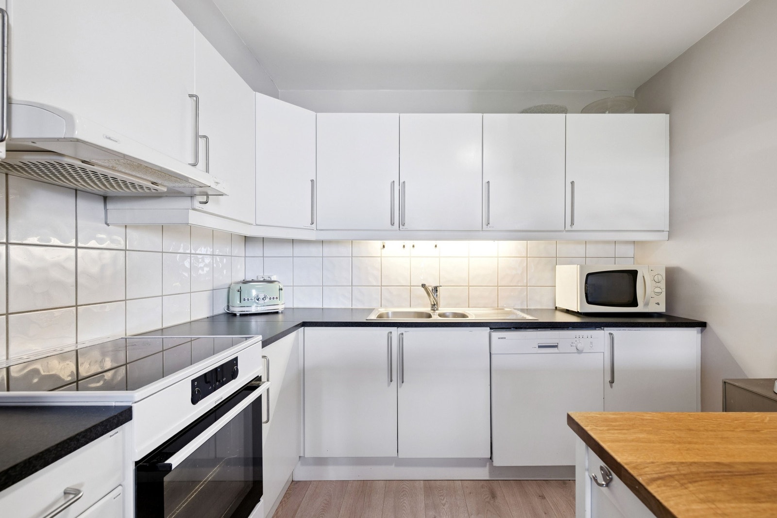 Lyst kjøkken med rikelig over- og underskap Galleribilde