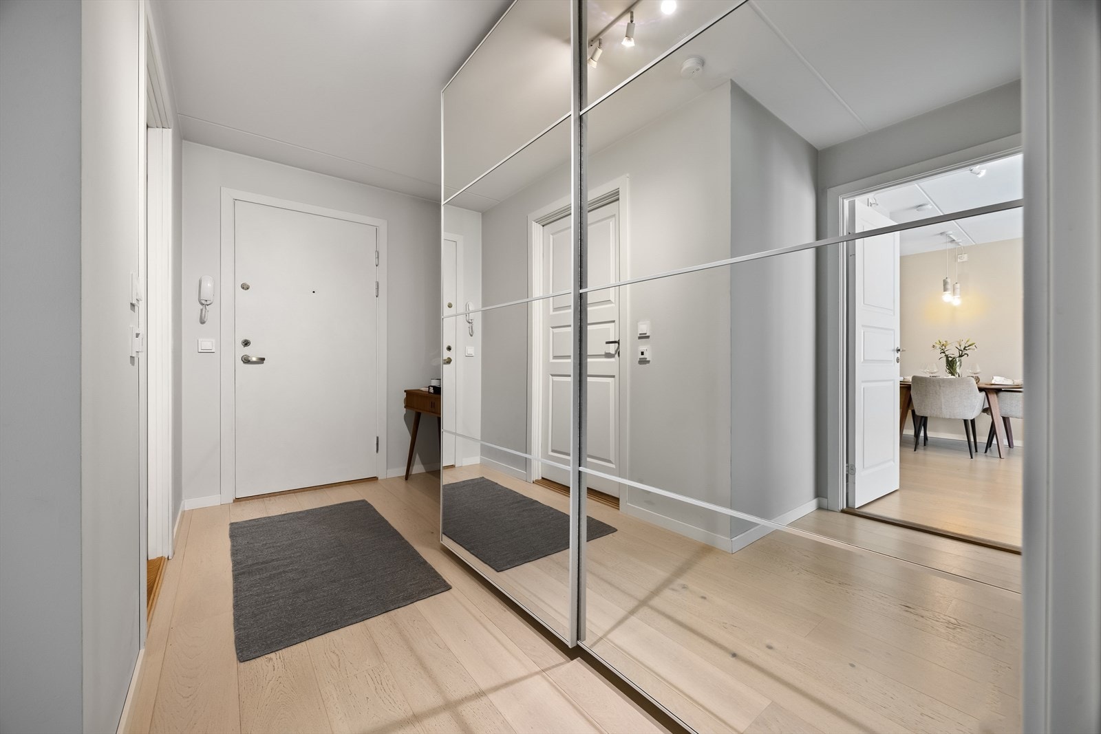 Romslig entré med praktisk skyvedørsgarderobe med speil, både plassbesparende og stilfullt. Galleribilde