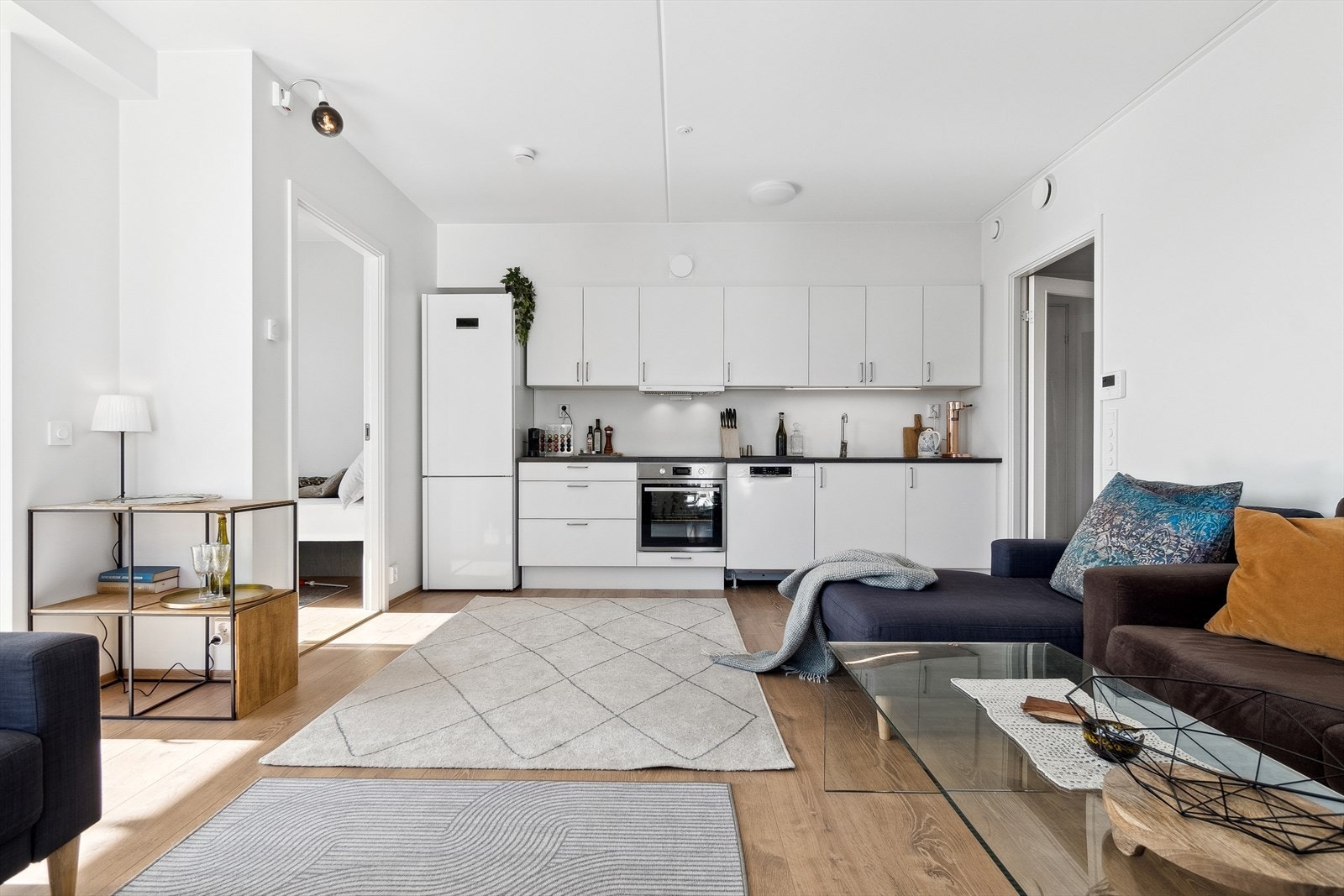 Kjøkkenet har klassisk åpen løsning ut mot stuen med hvite slette fronter og stilrett, brytende laminat benkeplate og nedfelt vask. Galleribilde