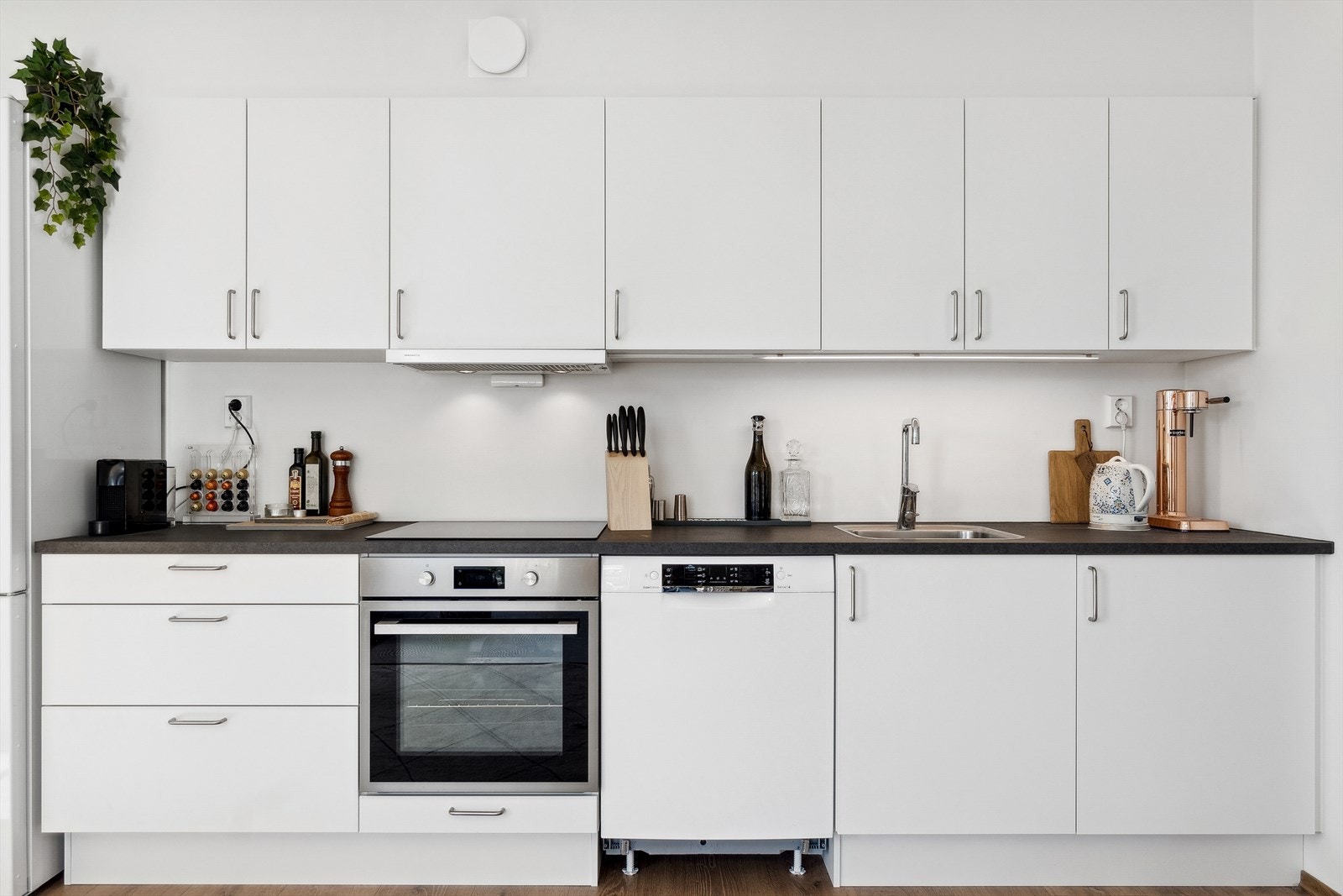 God oppbevaring i stor skap-/benkplass. Norema kjøkkeninnredning. Integrert platetopp og stekeovn. Frittstående oppvaskmaskin og kjøleskap. Galleribilde