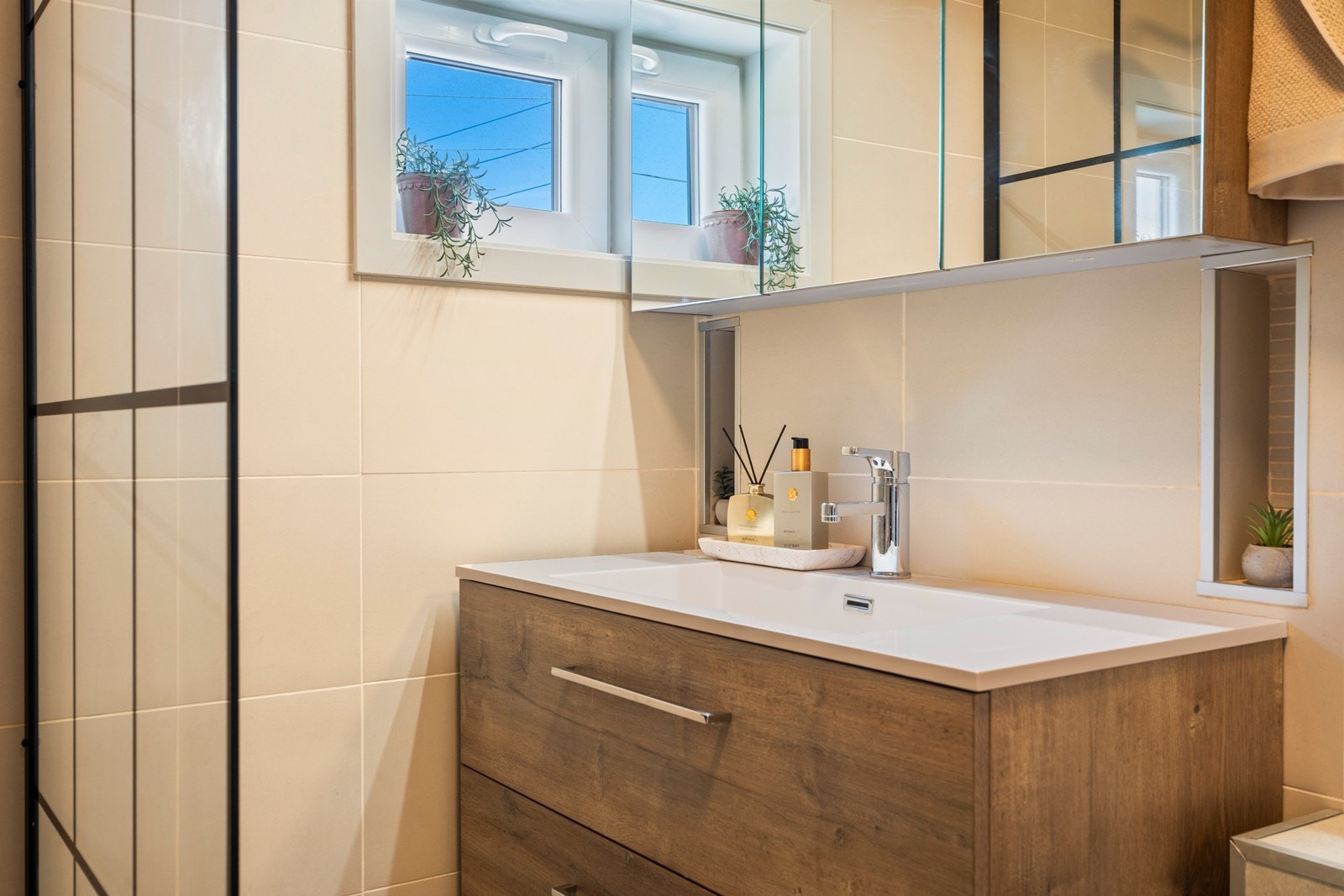Badet inneholder dusjnisje, innredning med servant, speilskap og toalett Galleribilde