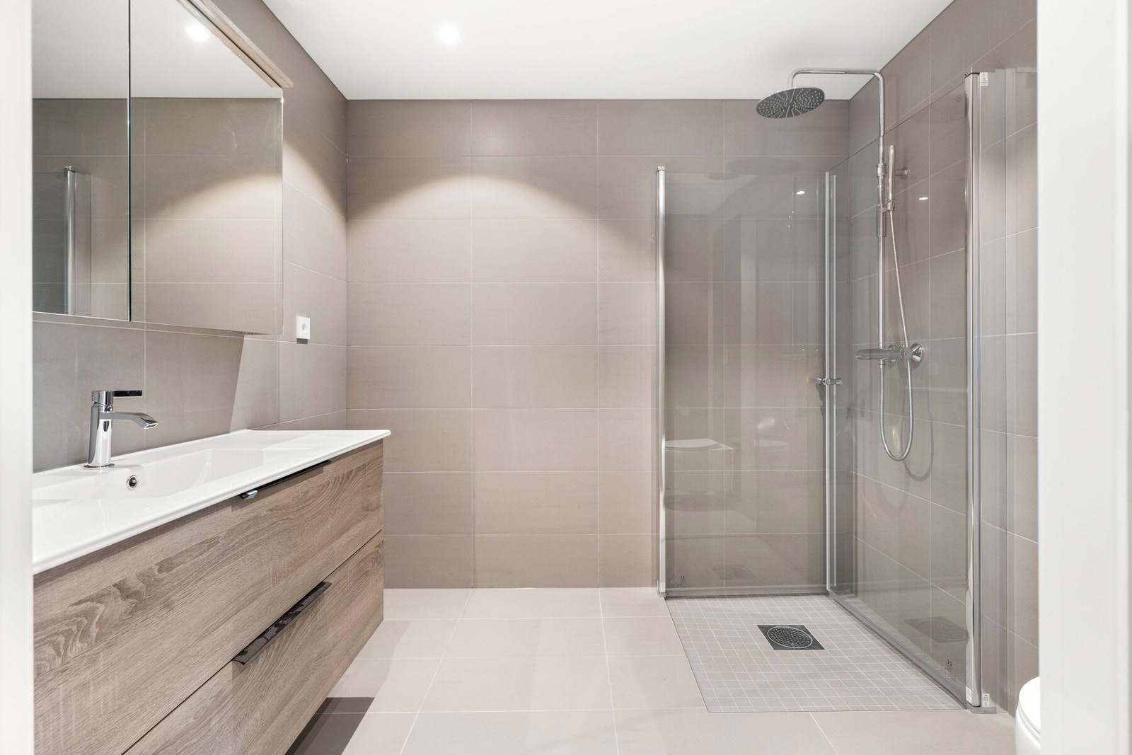 Romslig lekkert bad med servant og skap, dusjnisje og vegghengt toalett. Opplegg for vaskemaskin og tørketrommel Galleribilde