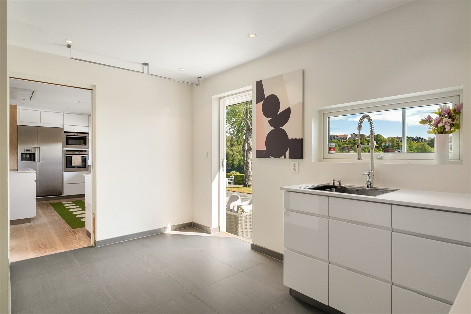 Praktisk planløsning med skyvedør mellom kjøkken og vaskerom, og inngang fra gang på motsatt side. Direkte utgang til hagen Galleribilde