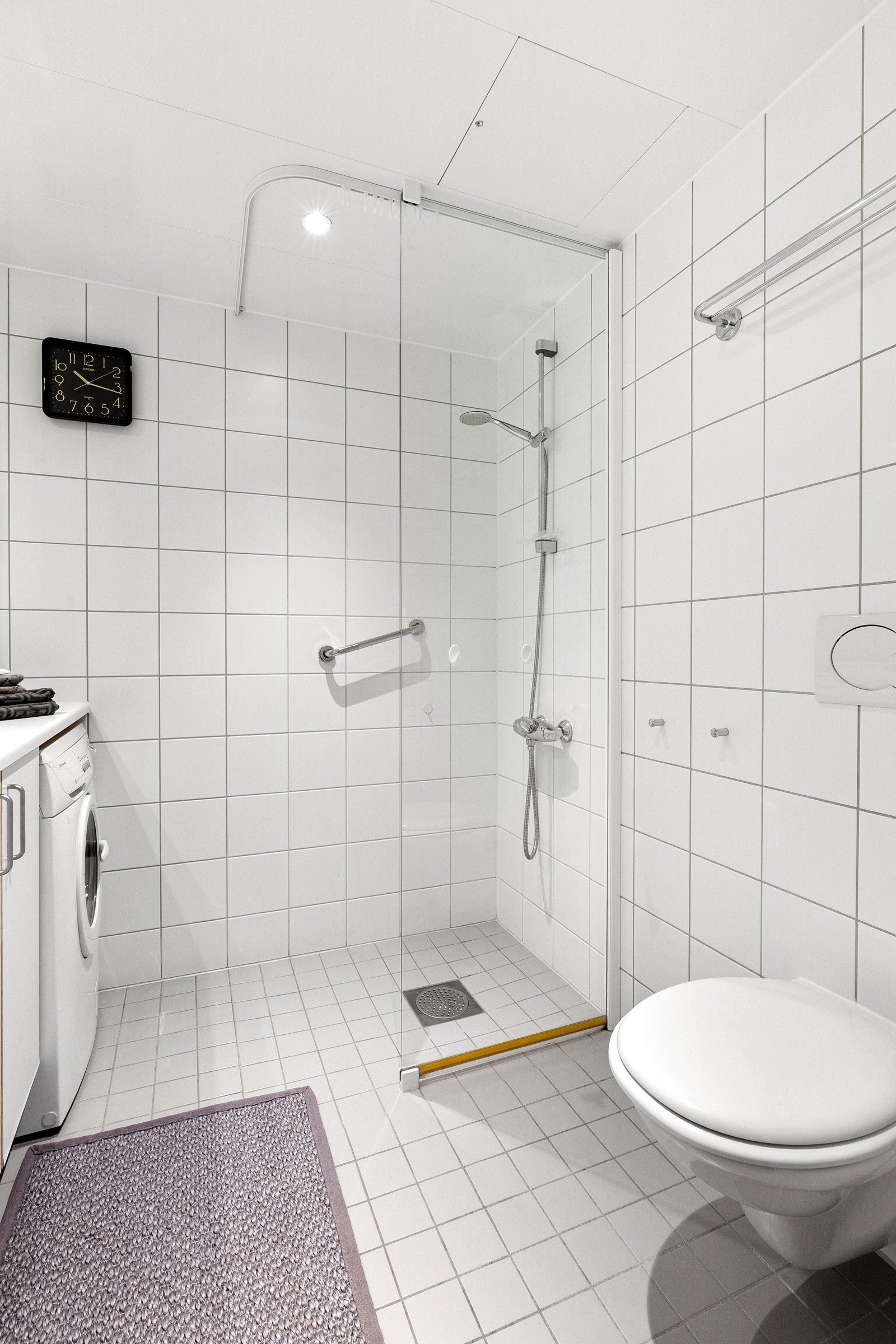 Badet fremstår innbydene med hvite fliser på vegger og gulv Galleribilde