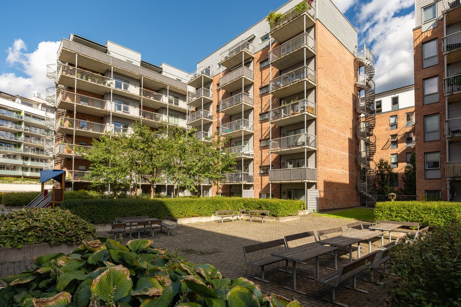 Felles tomt for borettslaget opparbeidet med steinlagte internveier, sittegrupper, trær og diverse beplantning. Galleribilde