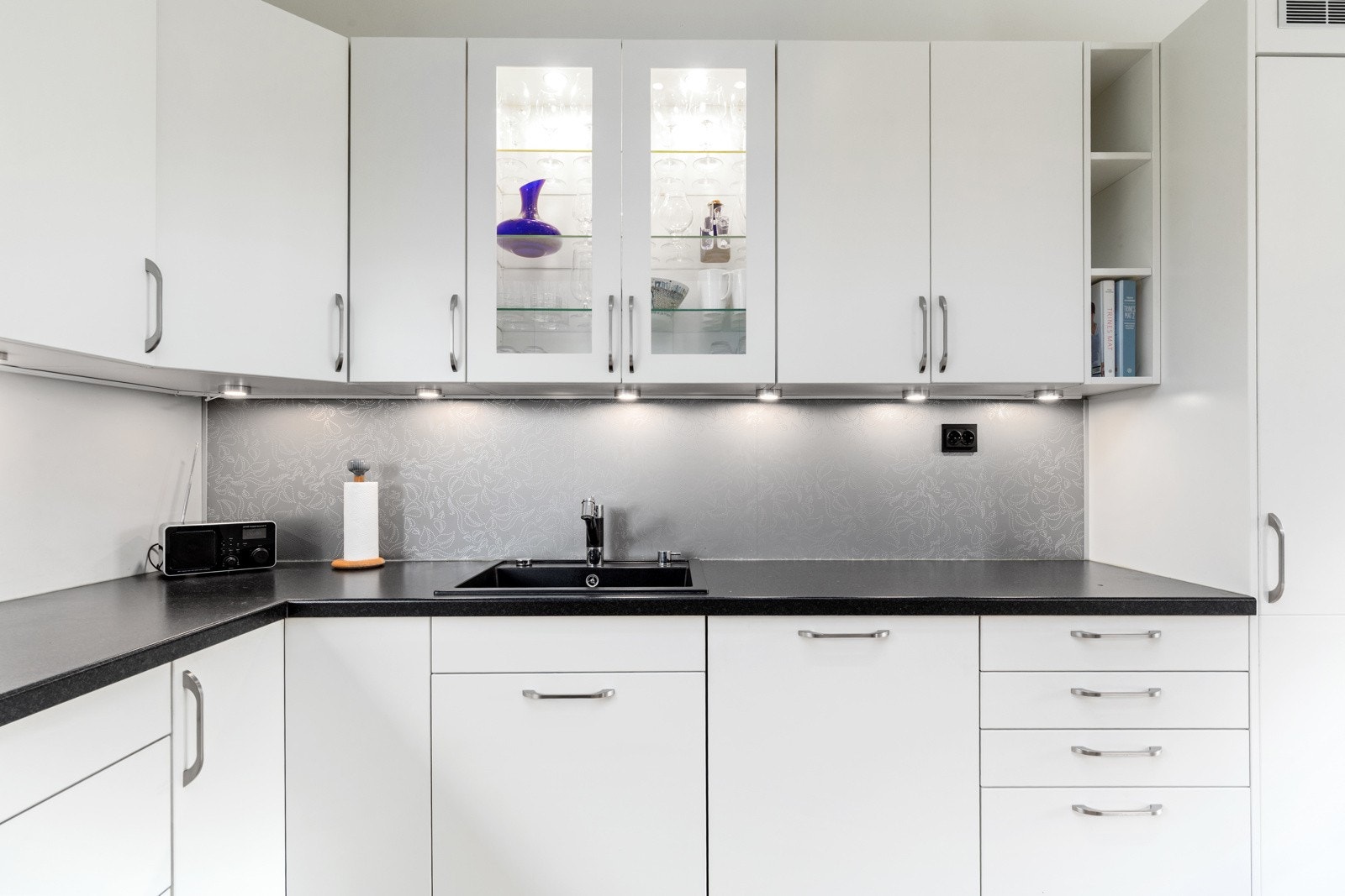 Kjøkkenet her slette, hvite fronter med integrert stekeovn, mikro, kjøleskap og vinskap. Godt med benke- og skapplass. Galleribilde