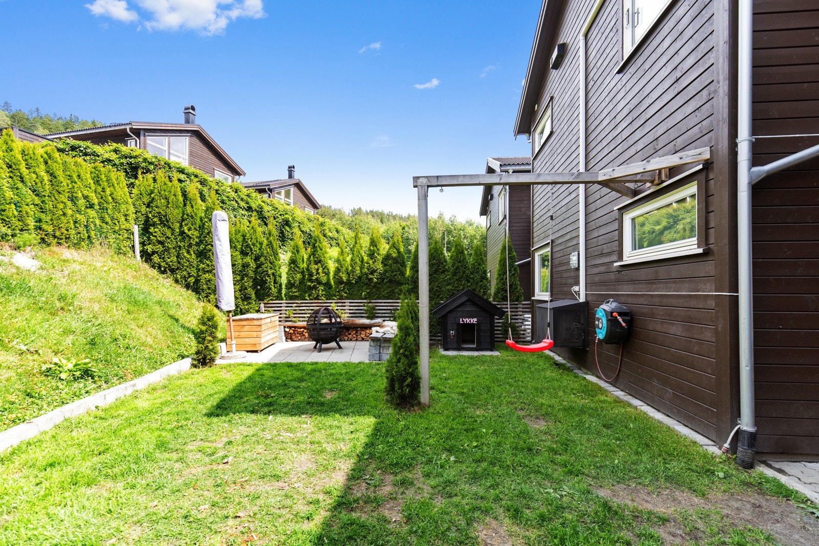 Hagen er pent opparbeidet med plen, steinlagt uteområde og hekk som skjermer for innsyn Galleribilde