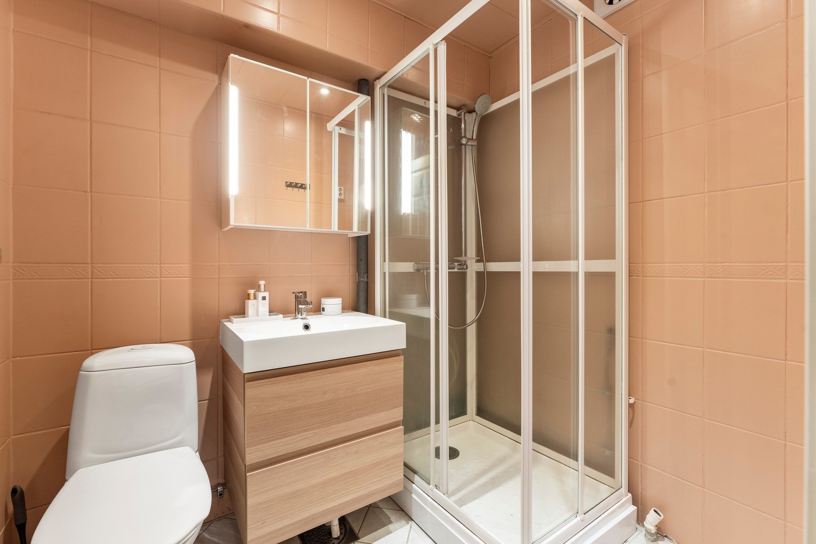 Badet er utstyrt med gulvvarme, toalett, dusjkabinett og en stilren servantinnredning - riktignok av eldre årgang med malte vegger fra nyere tid. Galleribilde