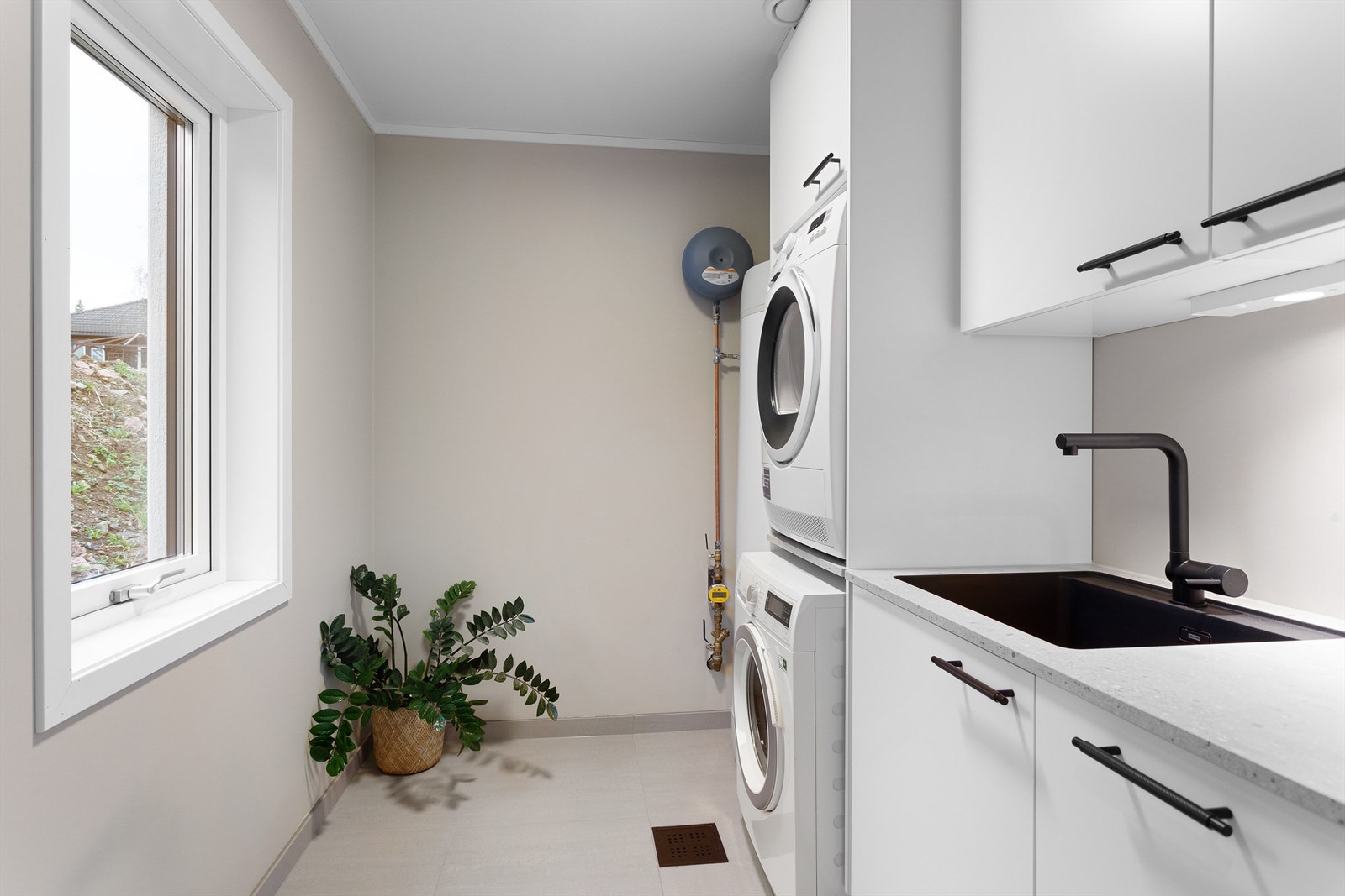 Vaskerom i tilknytning til inngangspartiet med vaskemaskin og tørketrommel i nisje, utslagsvask og varmtvannsbereder på 280L. Galleribilde