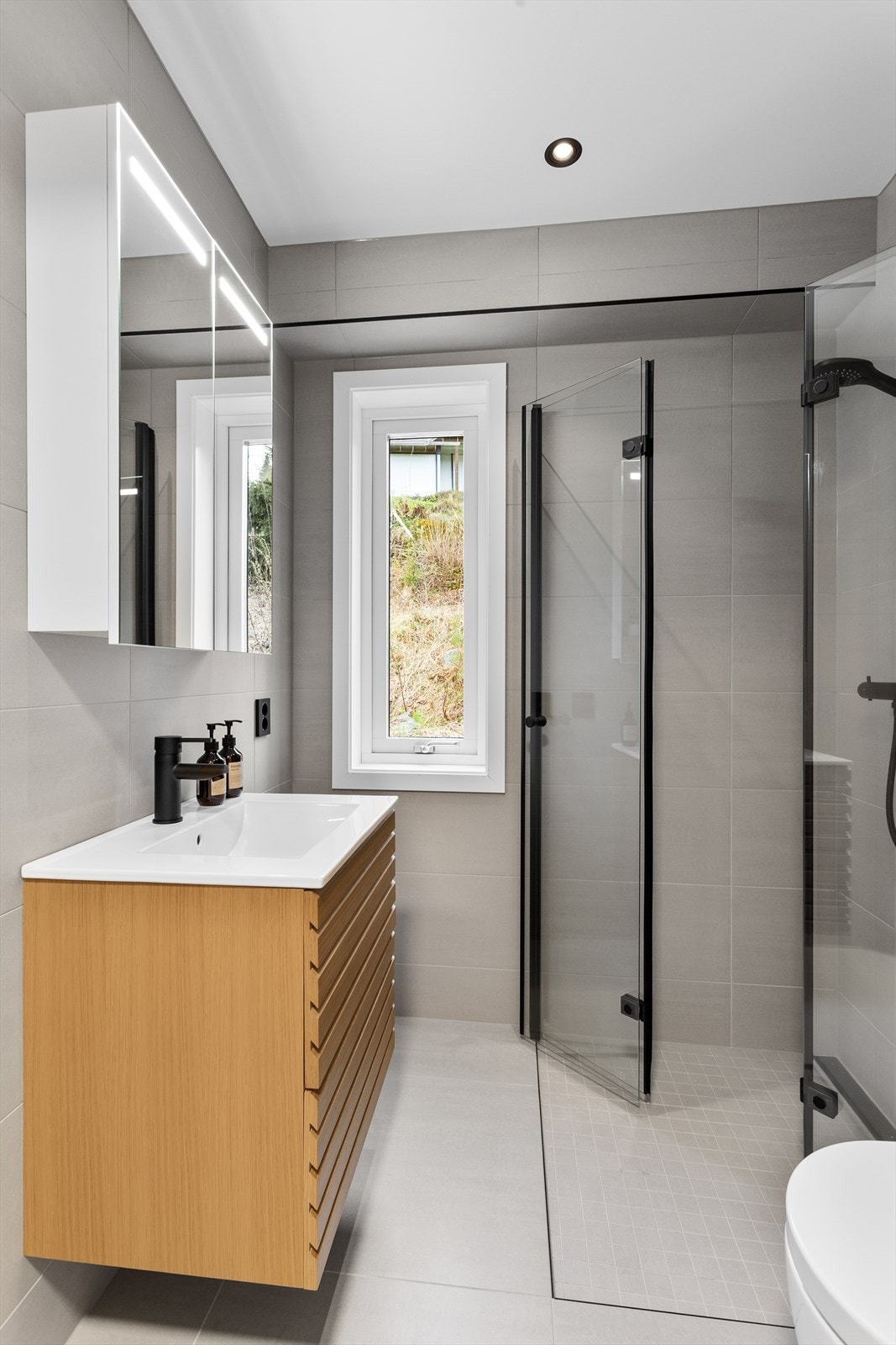 Lekkert flislagt bad med varmekabler, vegghengt toalett og servantinnredning. Galleribilde