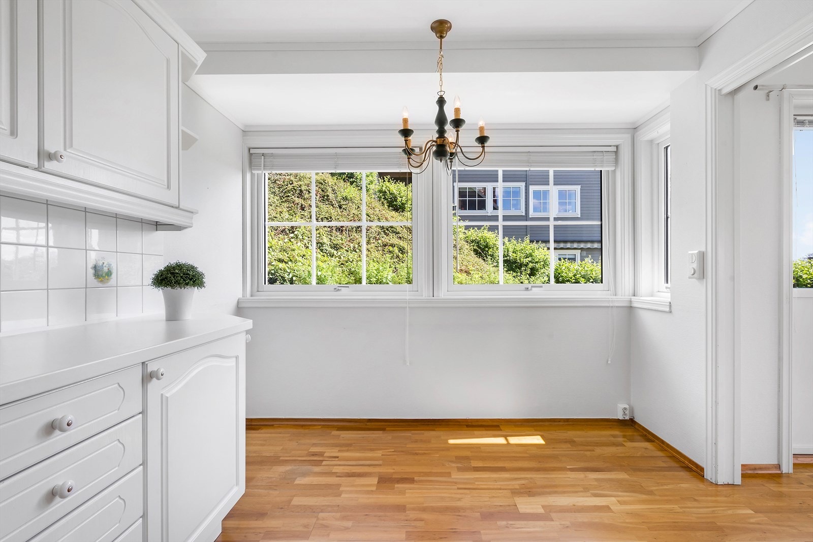 Lyst kjøkken med plass til et lite spisebord foran vinduet. Galleribilde