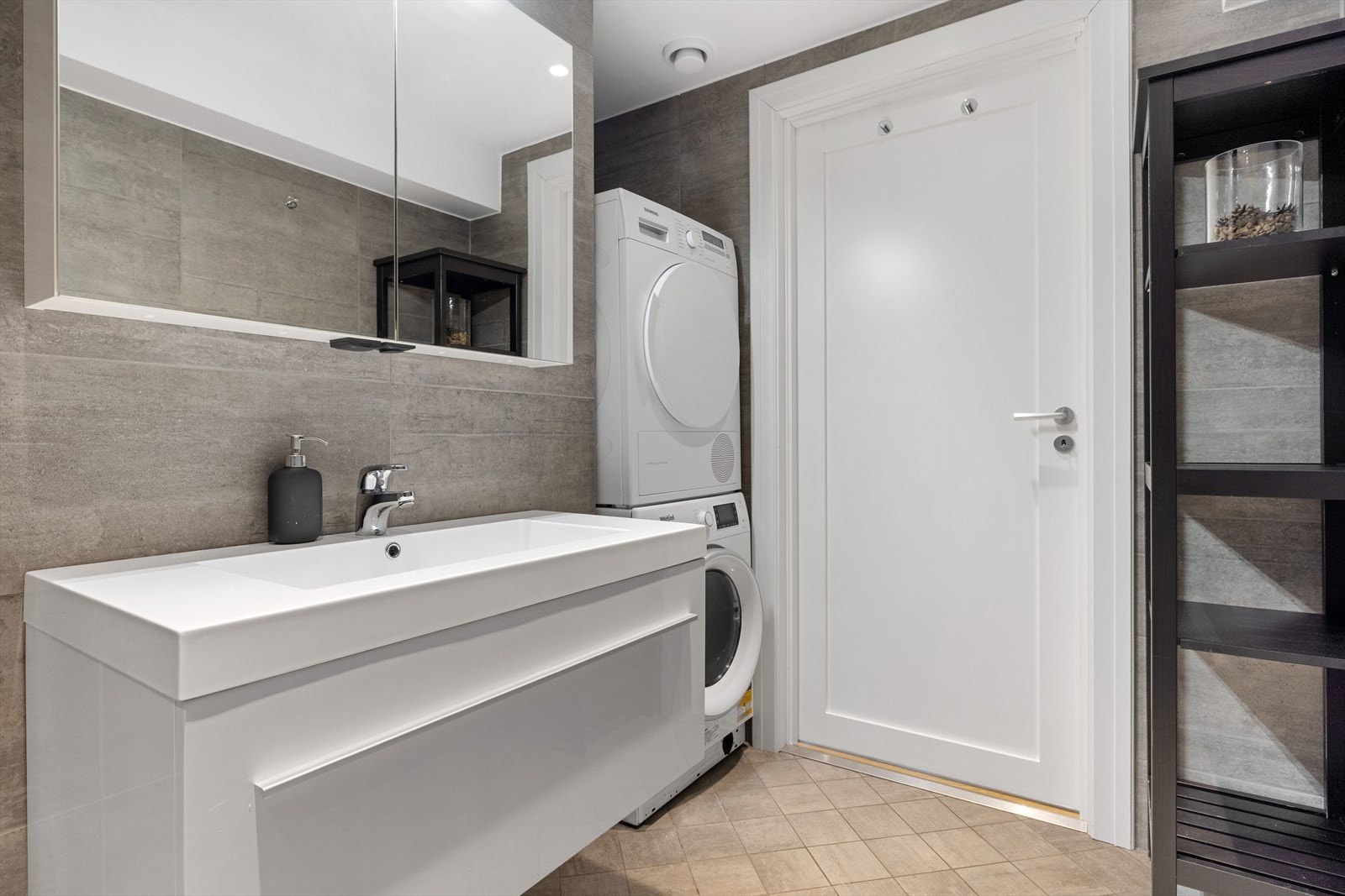 Badet har baderomsinnredning med skuffer og heldekkende servant med speilskap i overkant. En praktisk nisje for vaskemaskin og tørketrommel. Galleribilde