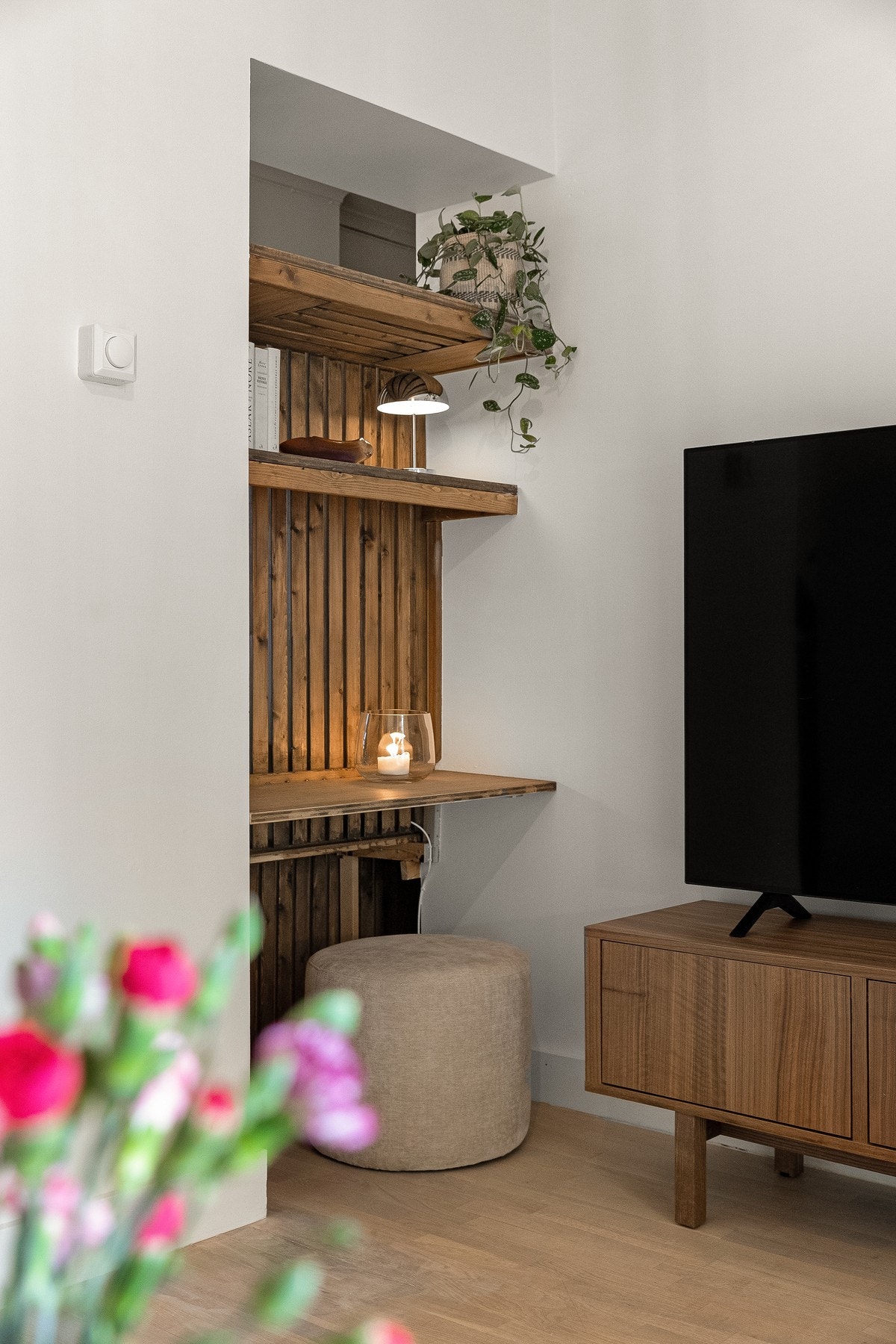 En fastmontert hylleløsning mellom stue og kjøkken gir både karakter og praktisk oppbevaring. Galleribilde