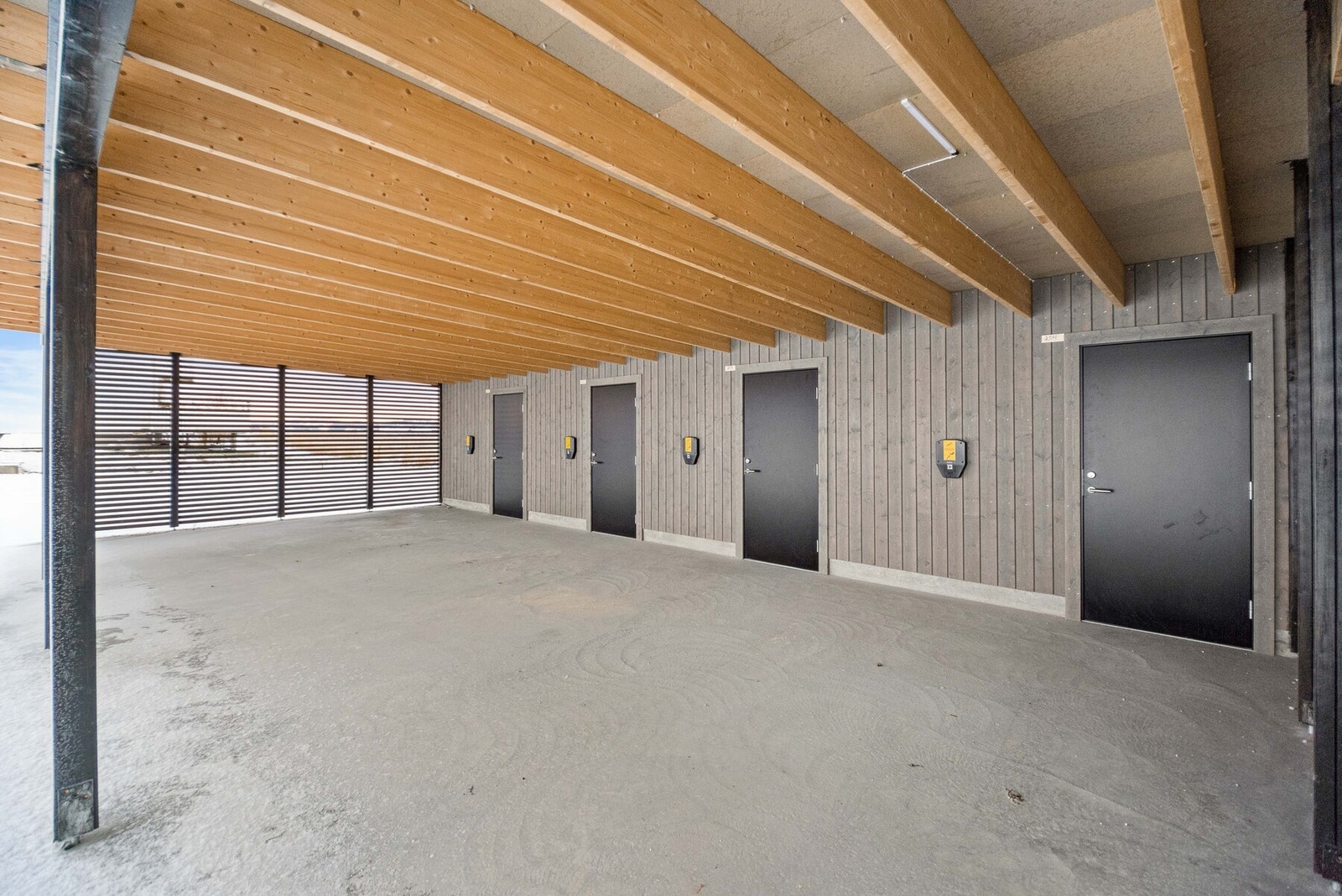 Parkering i carport med anlegg for elbillader. Sportsbod i bakkant av carporten. Galleribilde