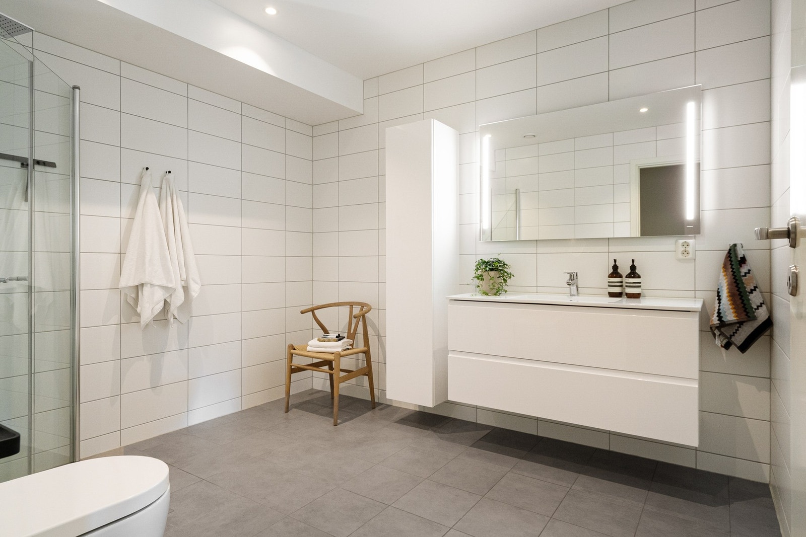 Flislagt bad med nedfelt servant, dusjhjørne og vegghengt toalett. Galleribilde