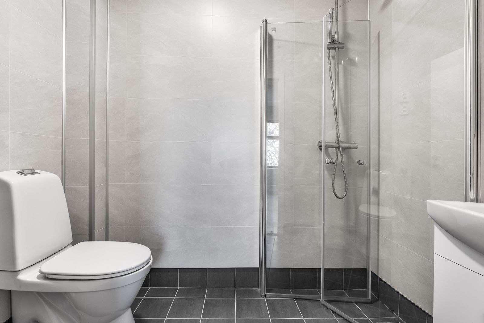 Flislagt bad med underliggende varmekabler og opplegg for vaskemaskin Galleribilde