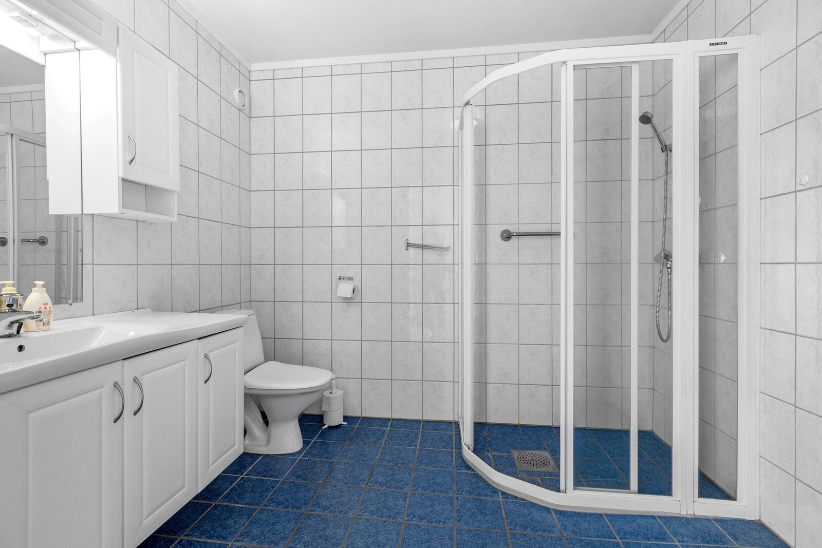 Praktisk bad med dusjhjørne, toalett, servant med innredning og opplegg for vaskemaskin. Galleribilde