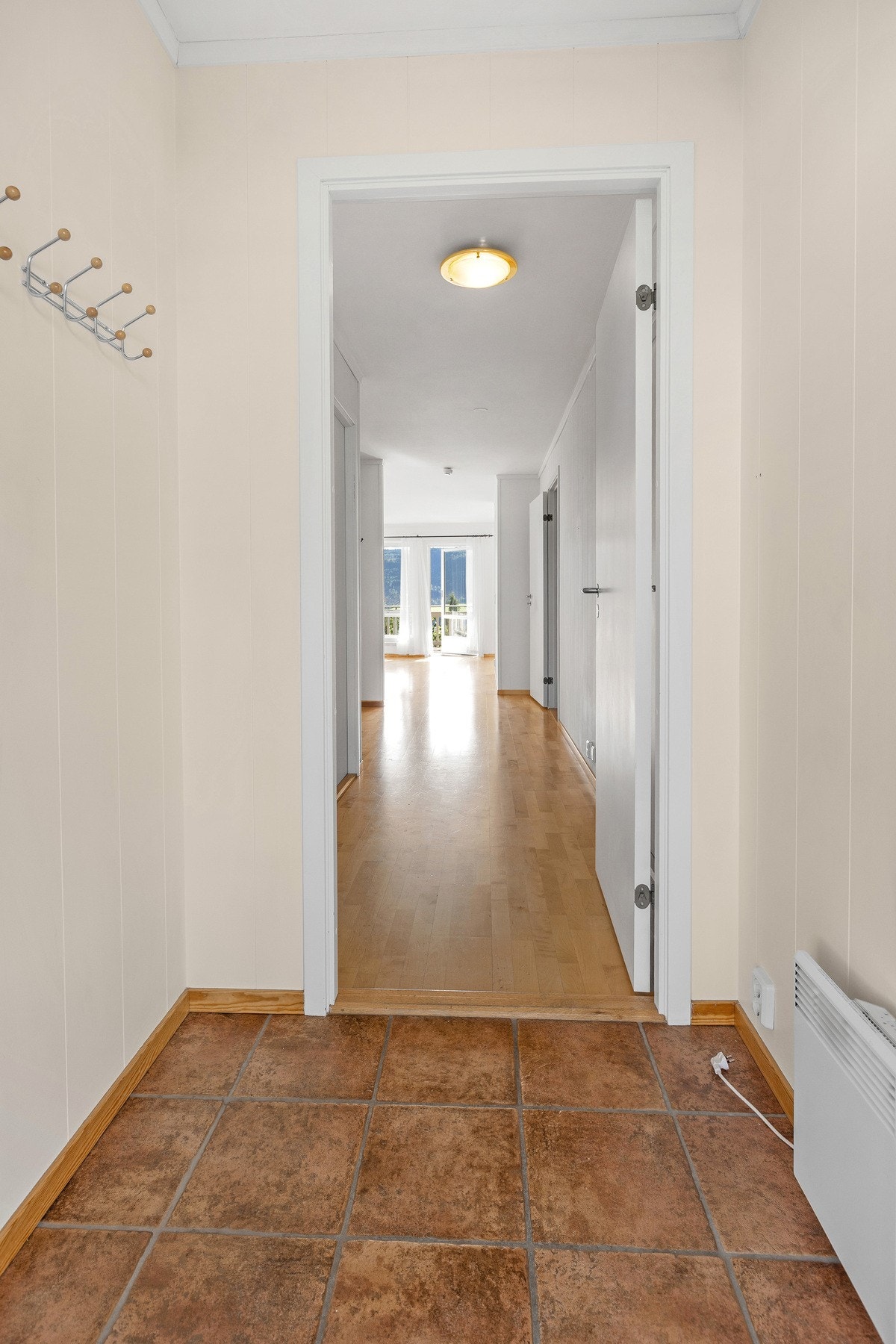 Praktisk entré med fliser og god plass til oppbevaring. Lyset fra stuen trekker deg videre inn i leiligheten. Galleribilde