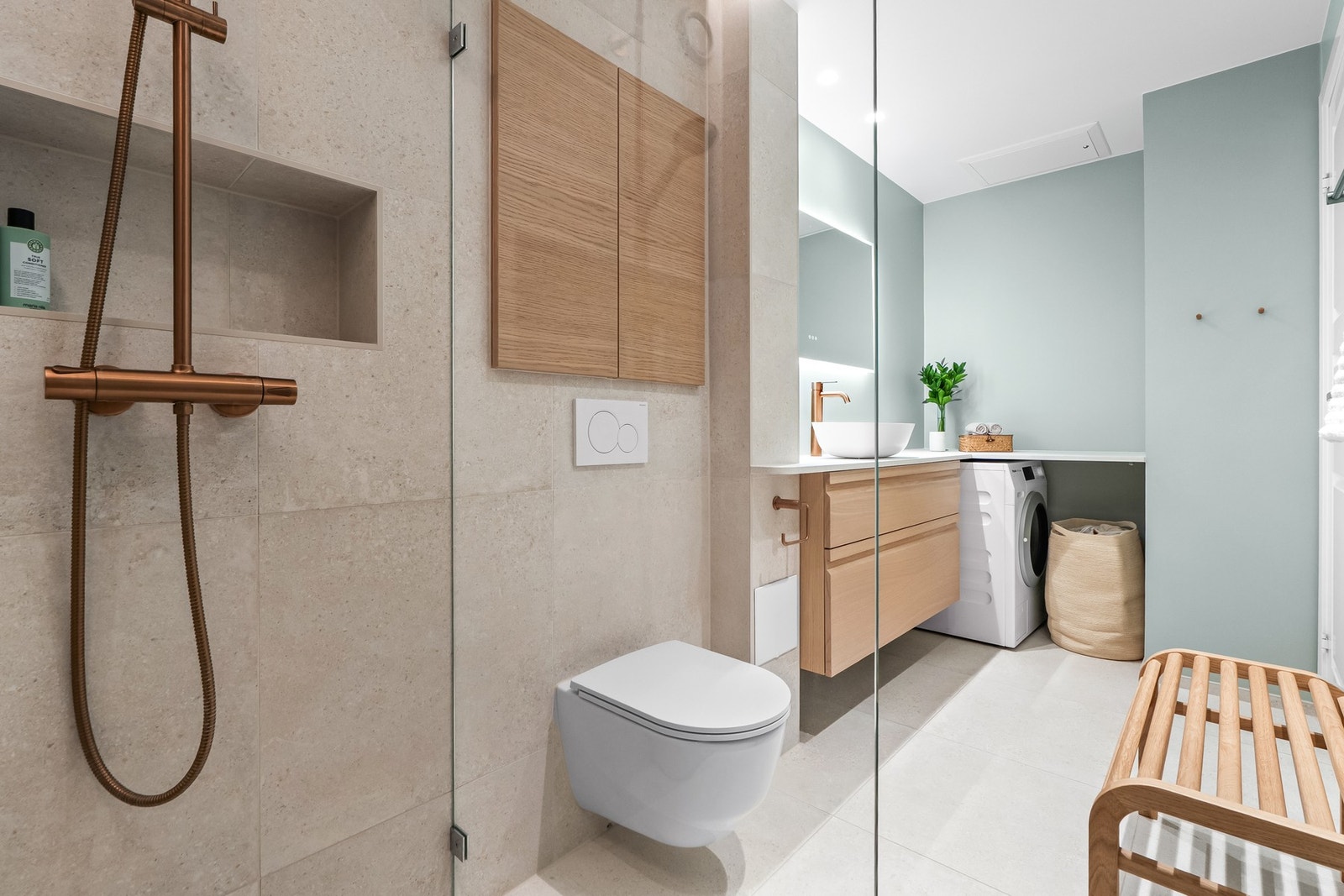 Det er vegghengt toalett, og i hjørnet er det benkeplate i L-form. Under er det skuffeinnredning og avsatt plass til vaskemaskin. Innredningen har fronter av heltre av drivtømmer med gripekant og soft-close. Galleribilde