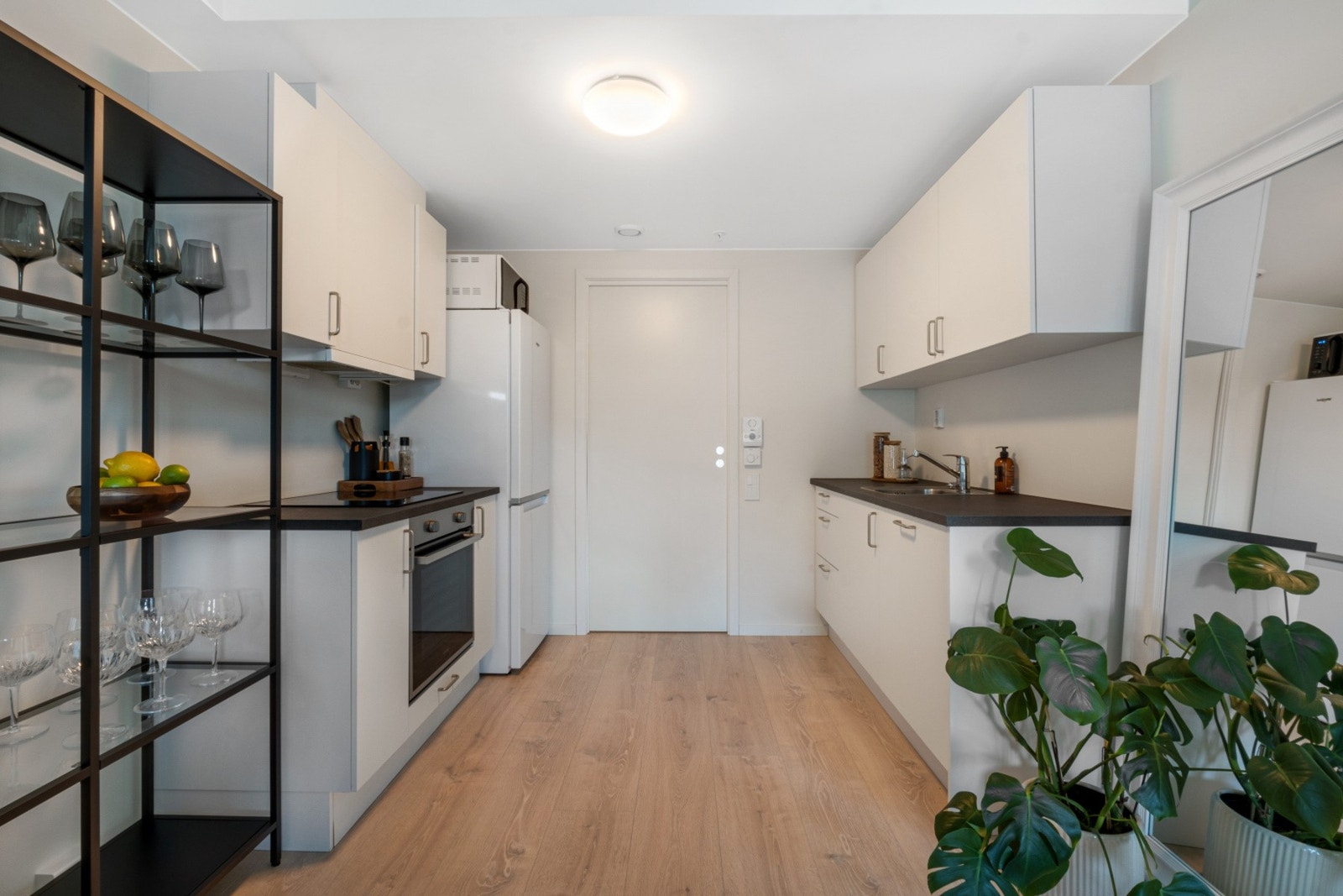 Kjøkkenet er innredet med hvite slette fronter, sort laminat benkeplate, nedfelt oppvaskkum og integrert oppvaskmaskin. Galleribilde