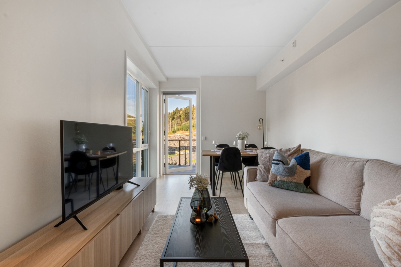 Den åpne løsningen gir godt med plass til både sittegruppe og spisestue, med direkte utsikt til det grønne området utenfor. Galleribilde