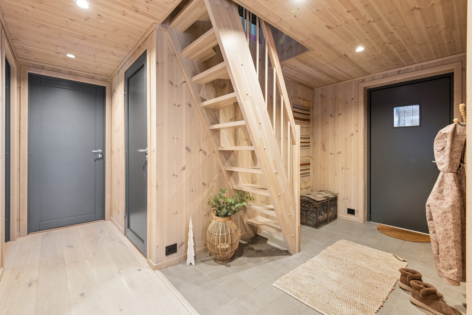 Flislagt gang med god plass til å henge fra seg klær og sette sko. Trapp opp til loftstua på hemsen. Galleribilde