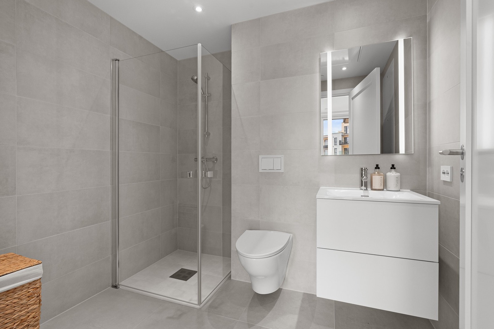 Pent flislagt bad med servantinnredning, vegghengt wc, dusjhjørne og opplegg til vaskemaskin. Galleribilde